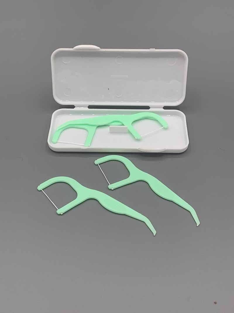 A pair of dental floss picks in a case on a gray surface.