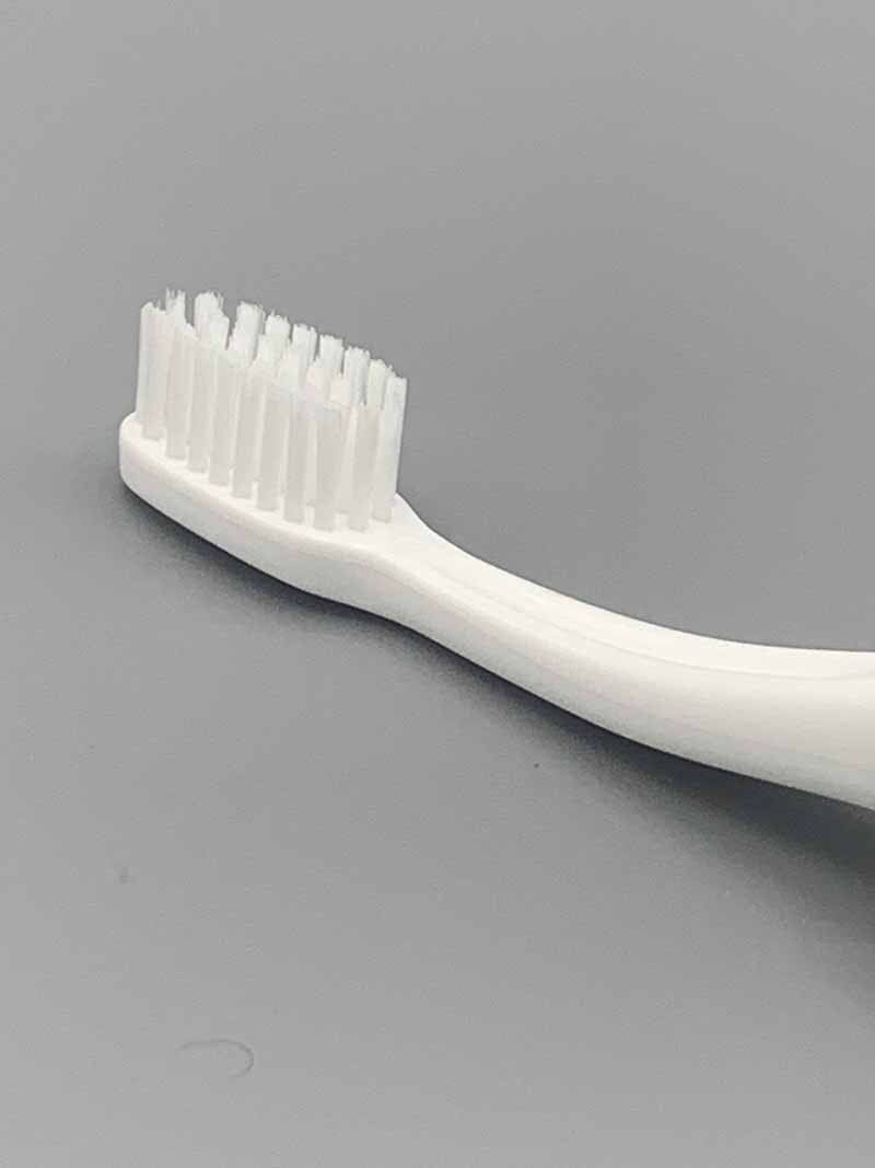 A close up of a white toothbrush on a gray surface.