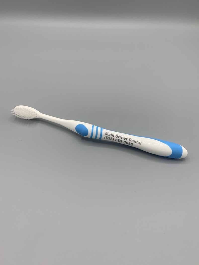 A white and blue toothbrush is sitting on a gray surface.