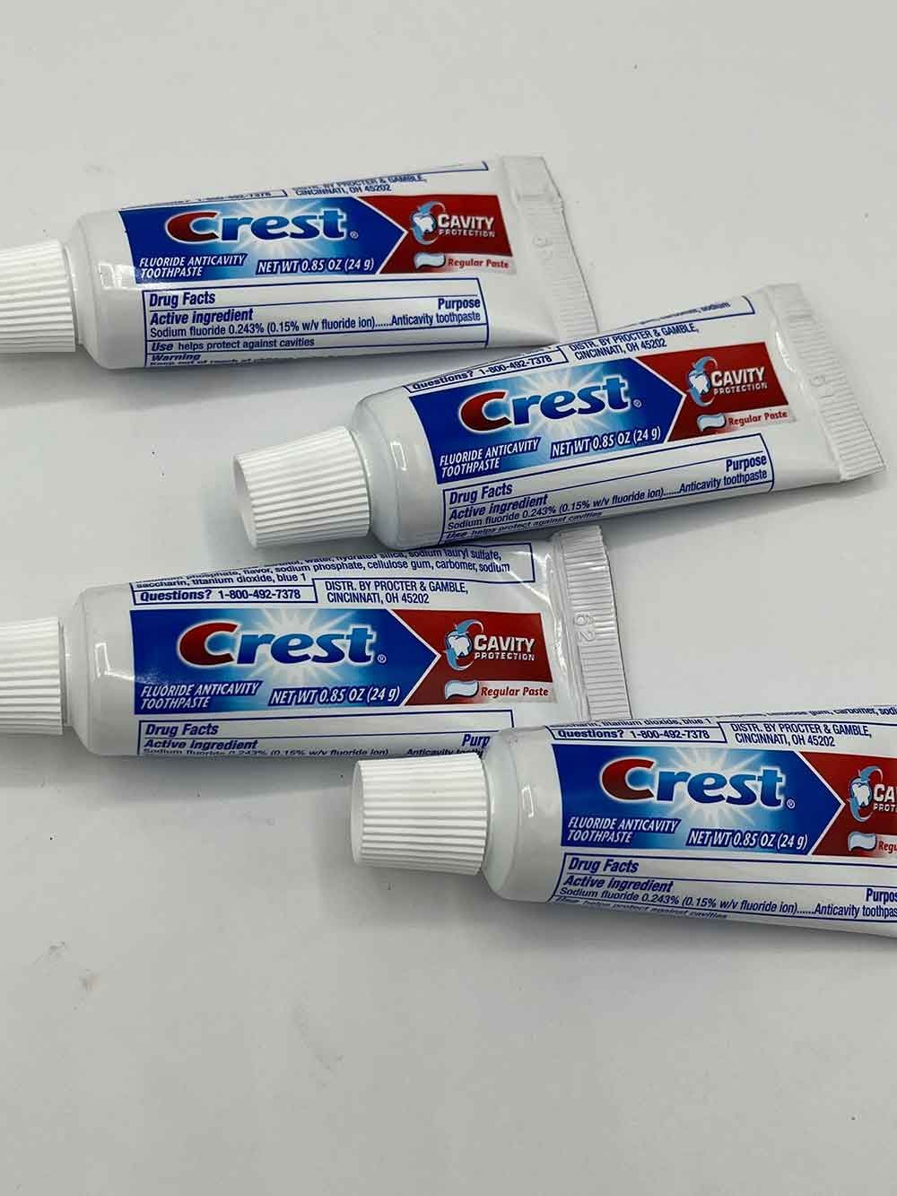 Four tubes of crest toothpaste are sitting on a table.