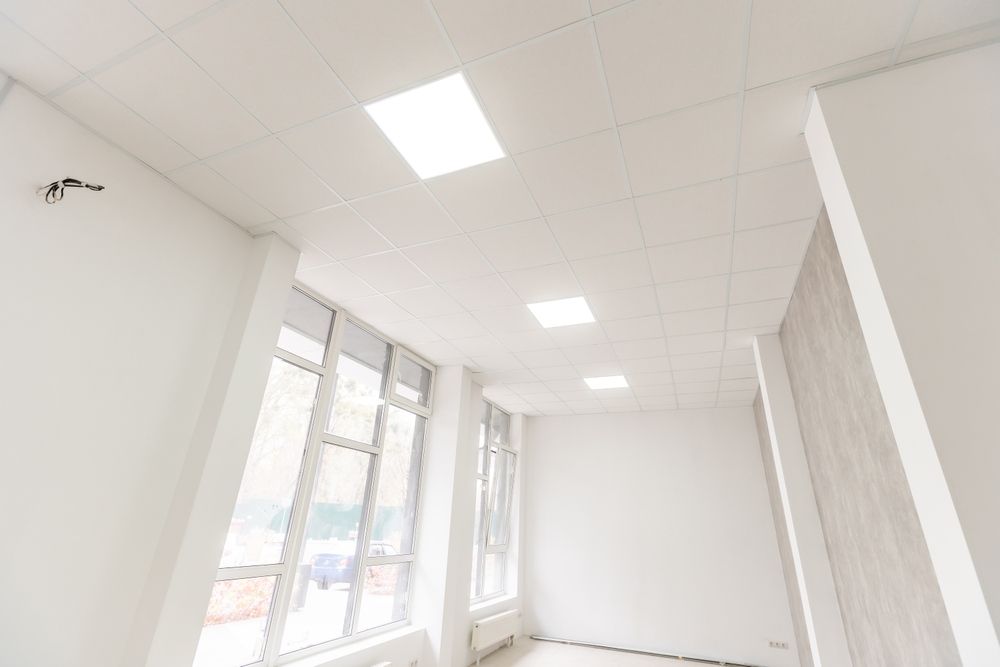 Bright, empty white room with large windows and ceiling lights in a modern building
