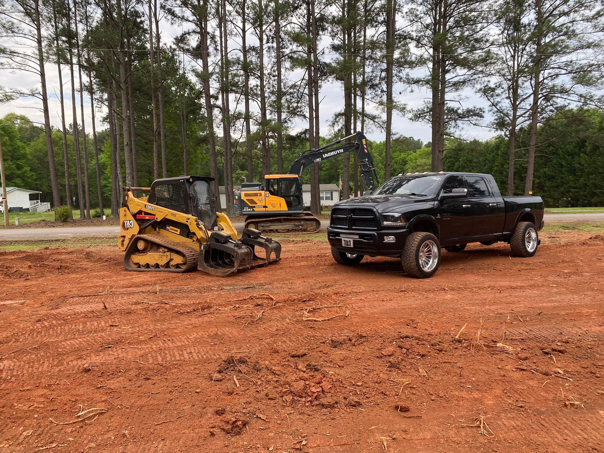 A black truck is parked next to a bulldozer in a dirt field.