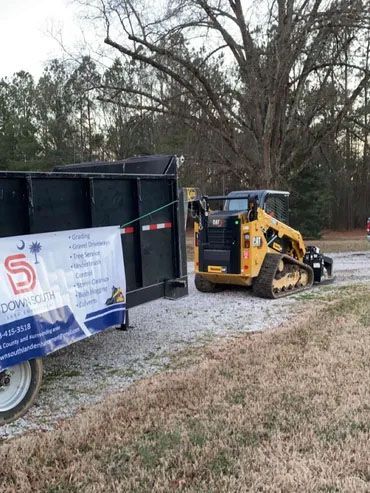 A bulldozer is parked next to a dumpster in a field.