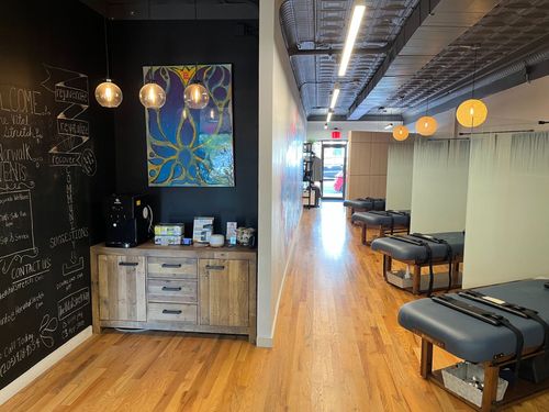 A row of massage tables in a room with a blackboard on the wall.