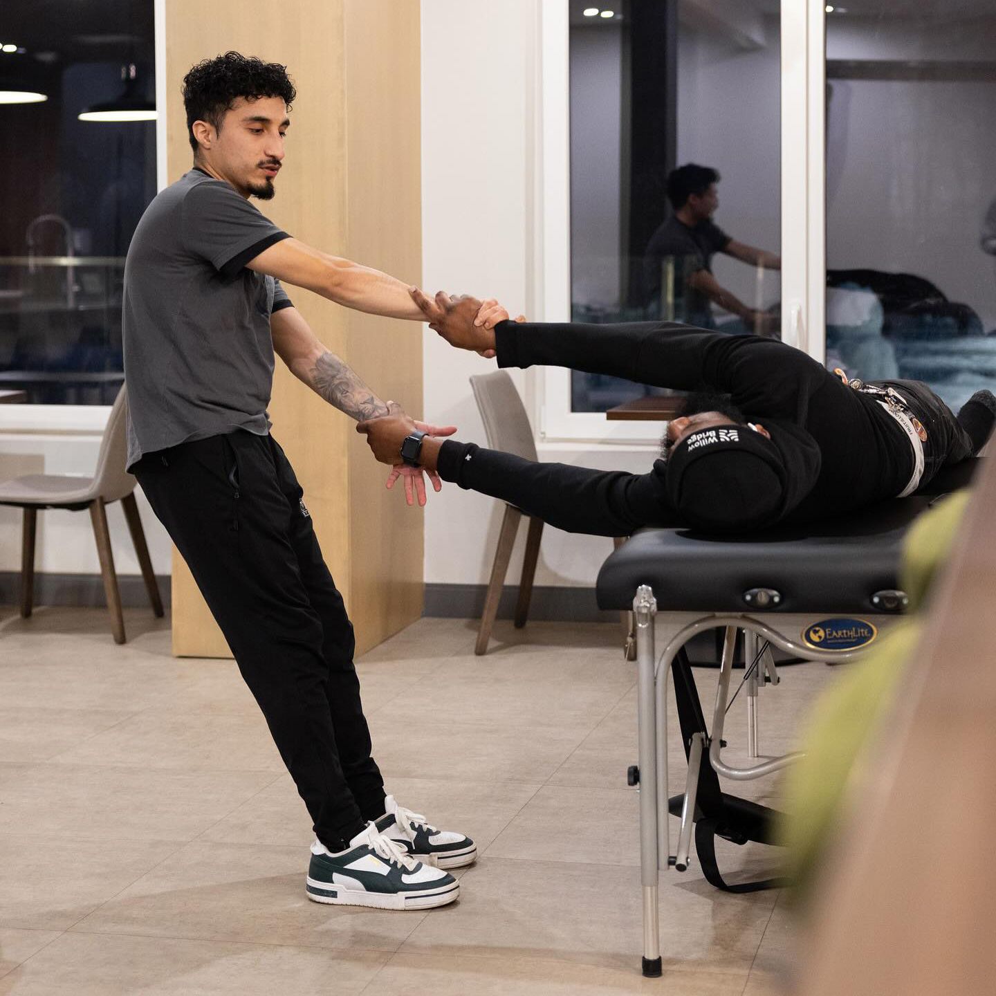 A man is stretching another man 's leg on a table