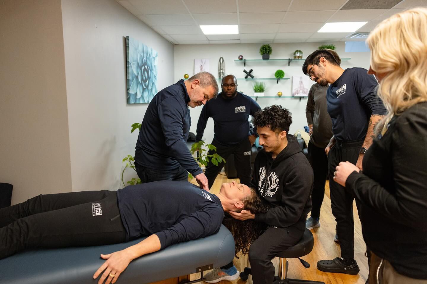 A group of people are standing around a woman laying on a table.