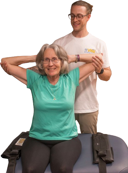 A man is helping an older woman stretch her arms