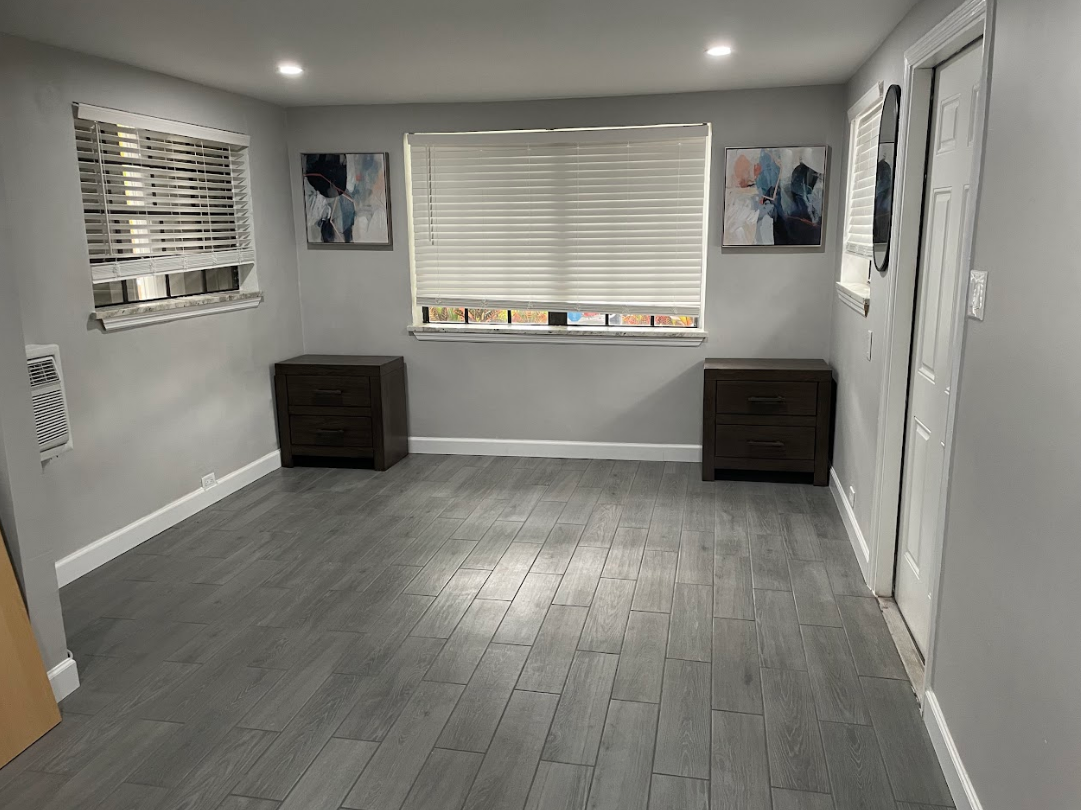 A living room with hardwood floors , two nightstands and a window.