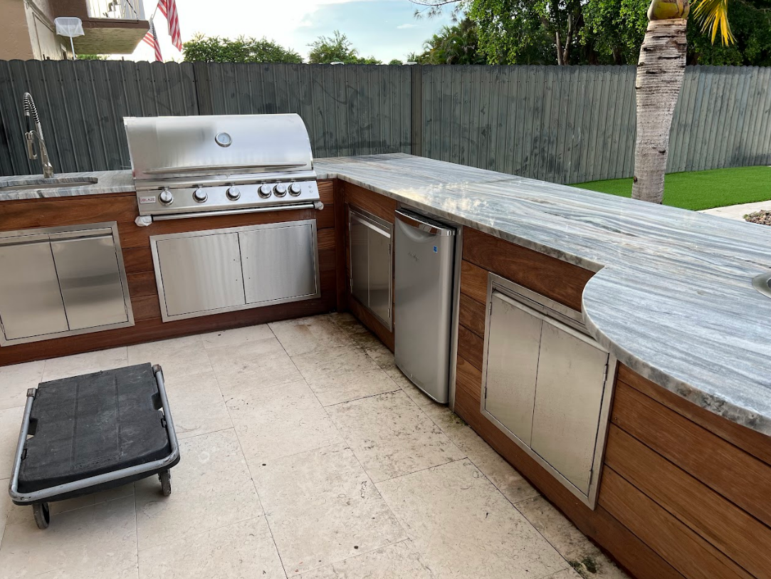 A large outdoor kitchen with a grill , sink , and dishwasher.