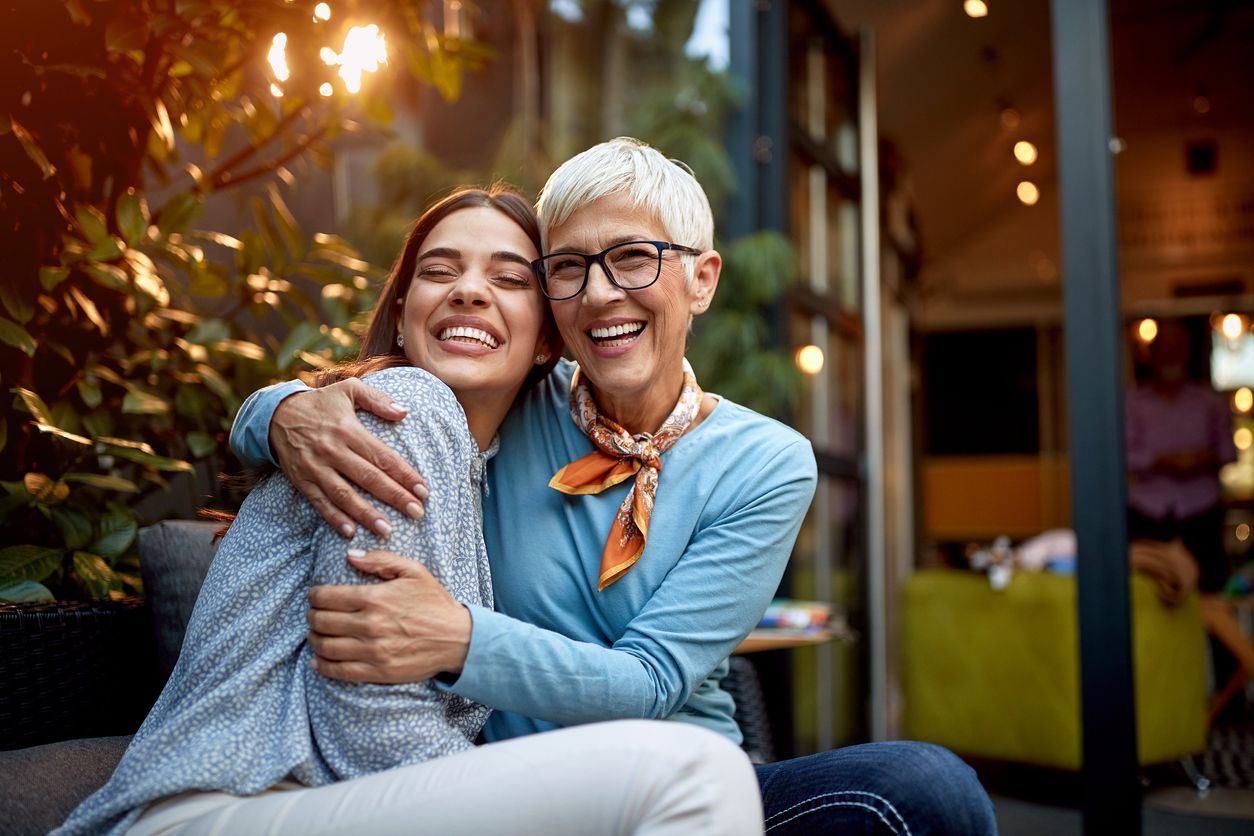 an older woman hugging a younger woman who is wearing glasses