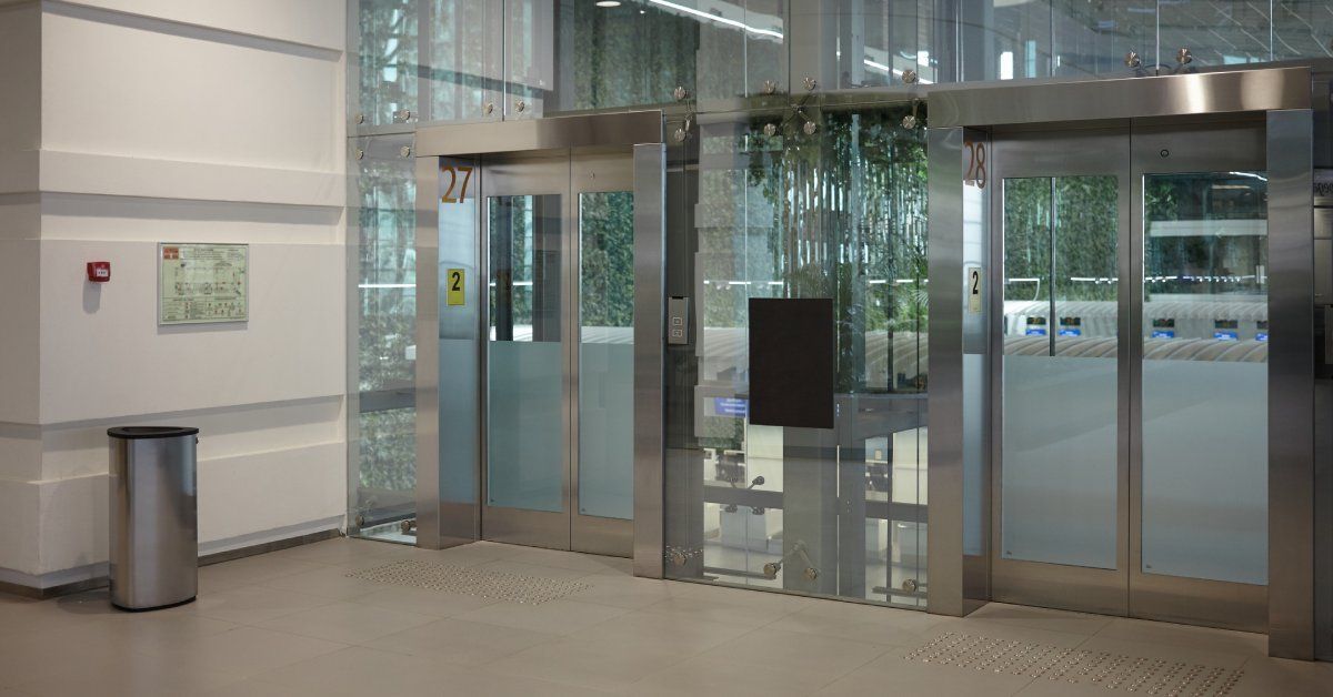 An inside view of a modern glass building's automatic sliding doors. The doors are entirely glass.