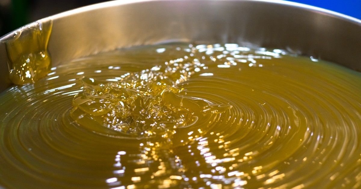 A blue drum filled with yellow, semi-translucent industrial grease featuring a spiral pattern with a