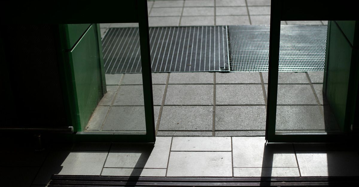 Close-up of automatic doors in action. Light shines in through the doors and onto the street pavemen