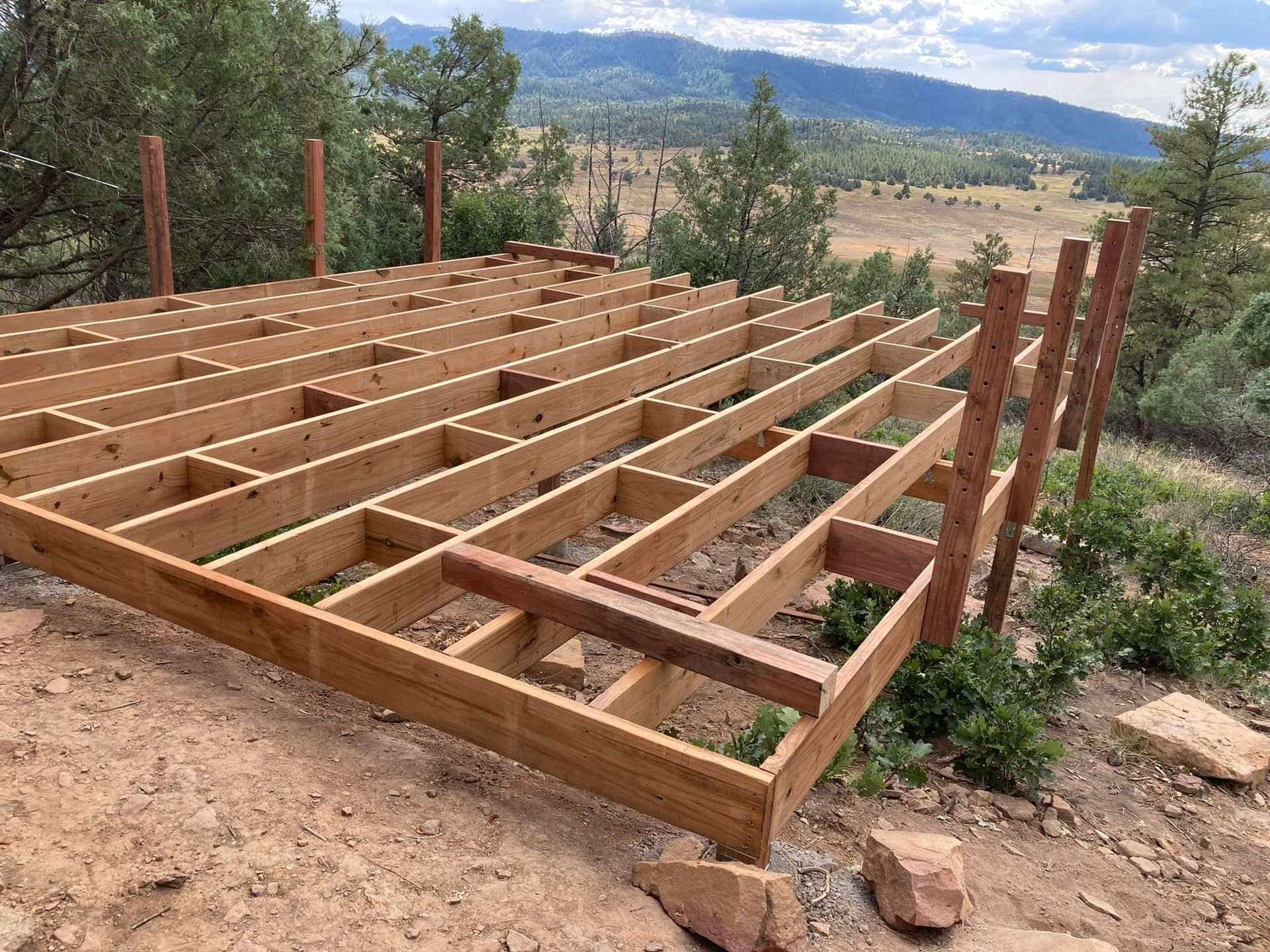 Wooden deck frame under construction outdoors with mountain view.