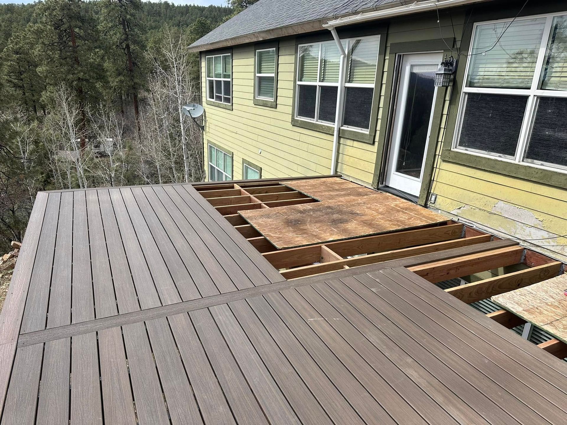 Deck partially under construction with missing boards; house in the background.