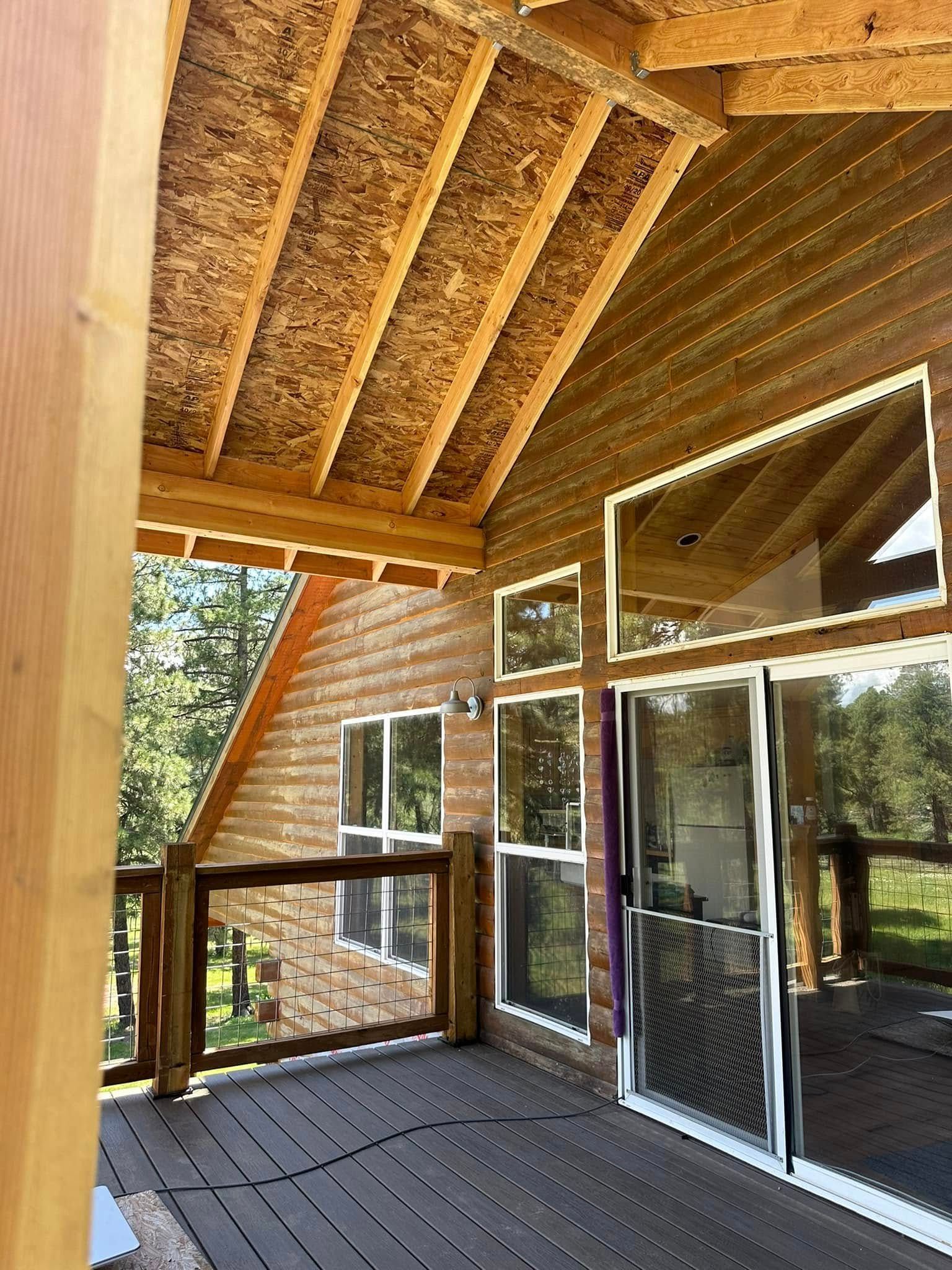 Wooden cabin deck with a view of trees through glass doors and windows.