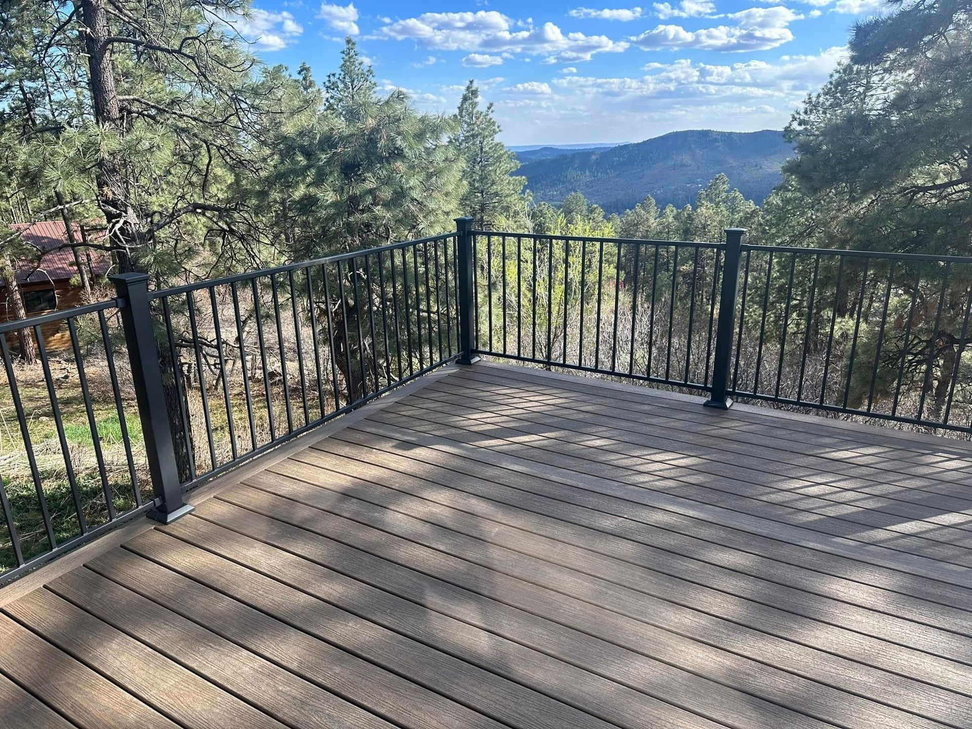 Deck overlooking a mountain vista; brown composite decking and black railing.