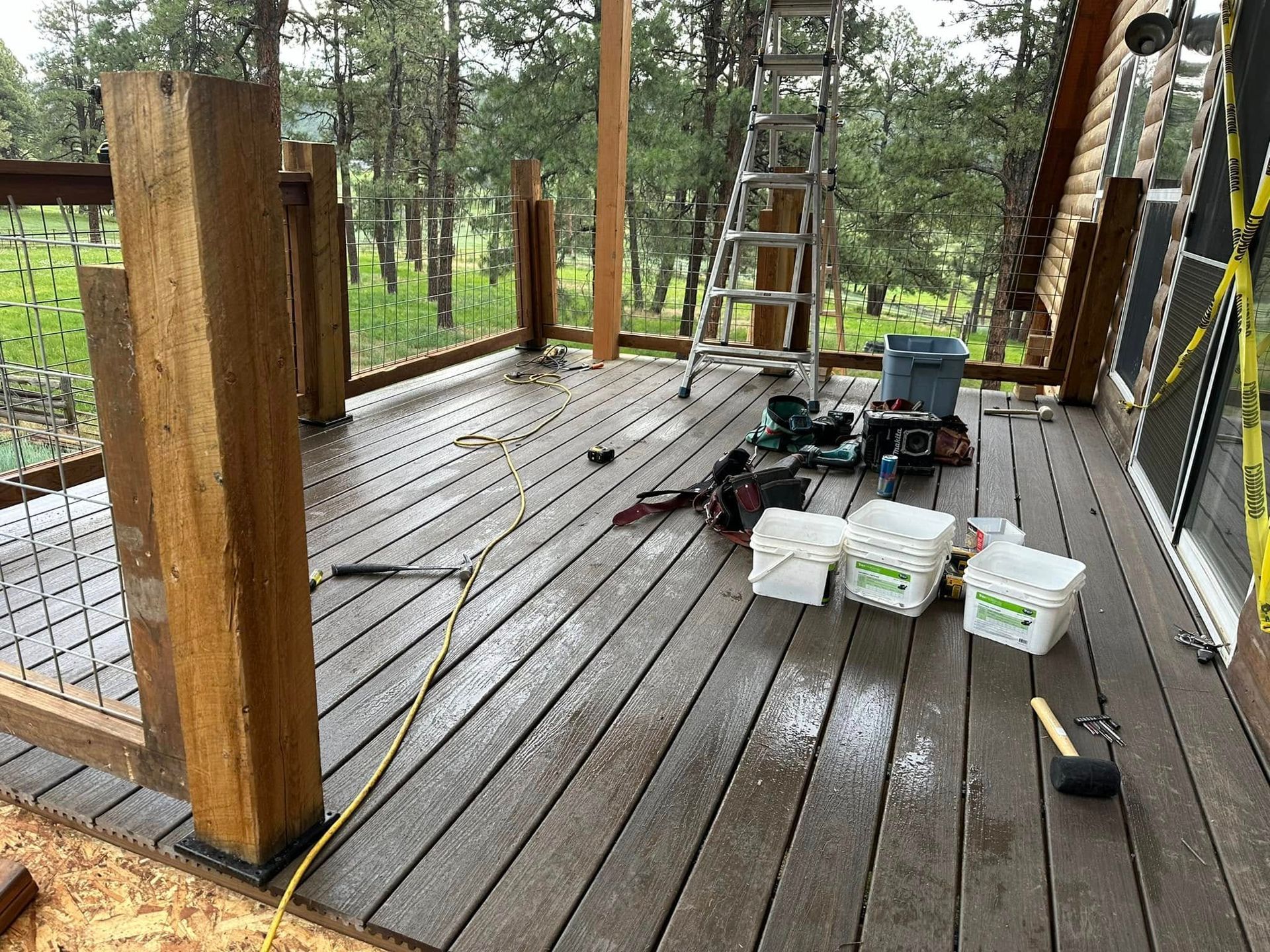 Deck under construction with tools, wood, and railing posts.