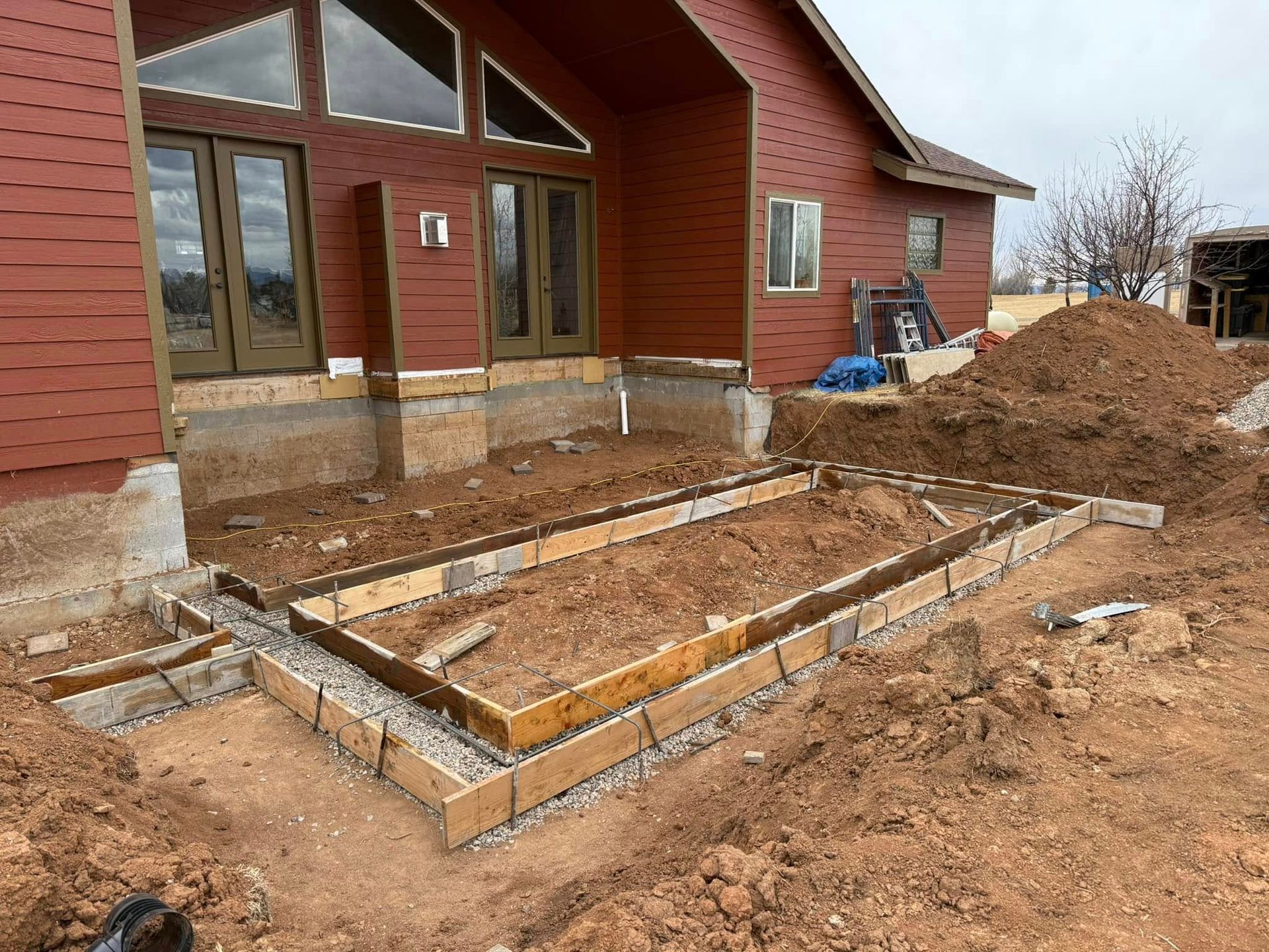 Construction site. Wooden forms set for concrete patio next to a red house.