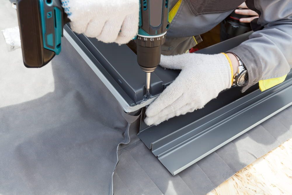A Man Is Using a Drill to Drill a Hole in A Piece of Metal — Rooftop Northern Rivers In Yamba, NSW
