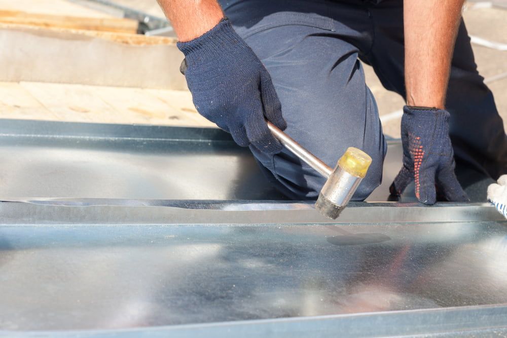 A Man Is Using a Hammer to Hammer a Piece of Metal — Rooftop Northern Rivers In Ballina, NSW