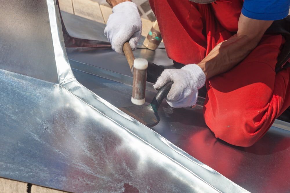 A Man Is Working on A Piece of Metal with A Hammer — Rooftop Northern Rivers In Ballina, NSW