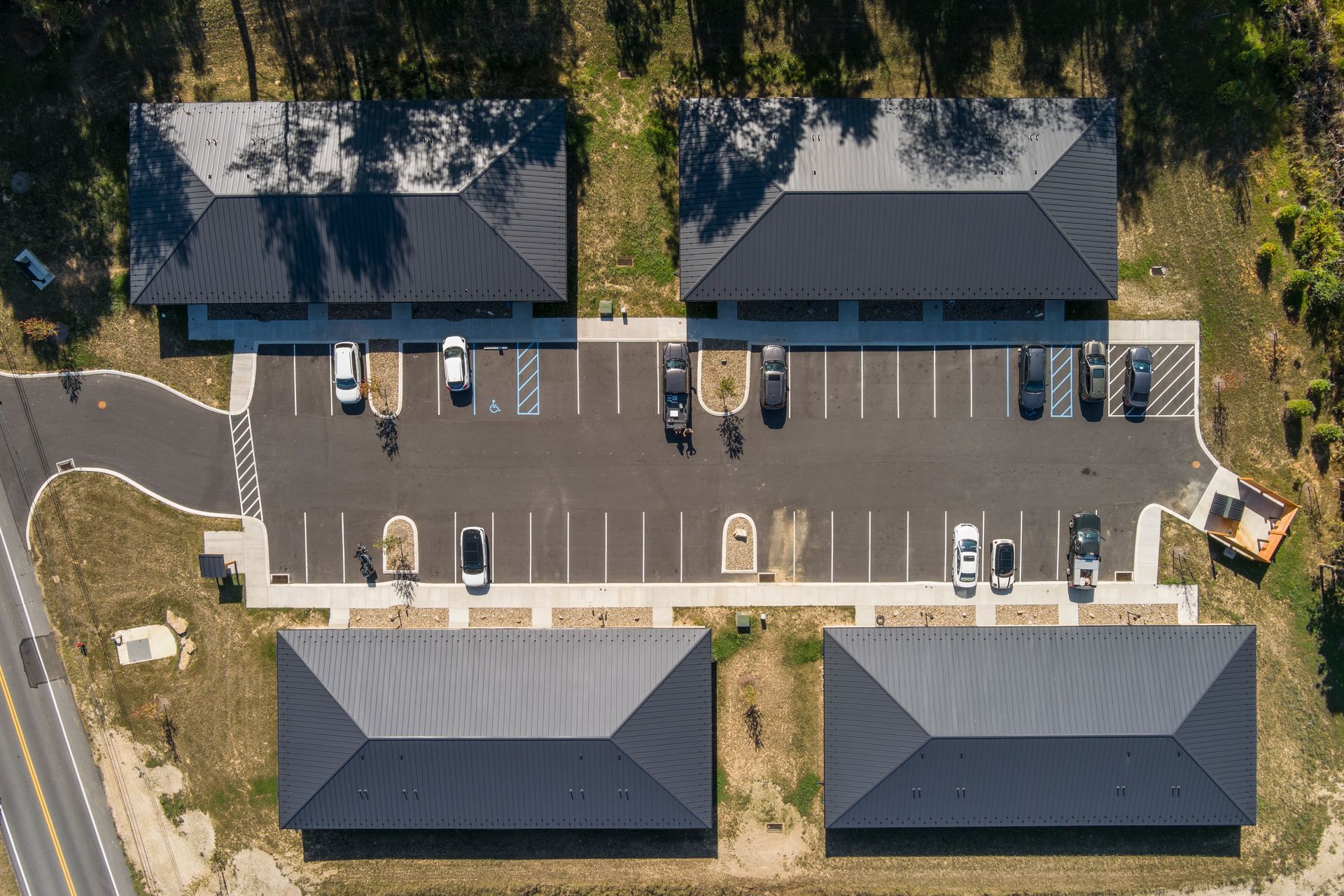 Aerial view of four detached buildings surrounding a central parking lot with several parked cars.