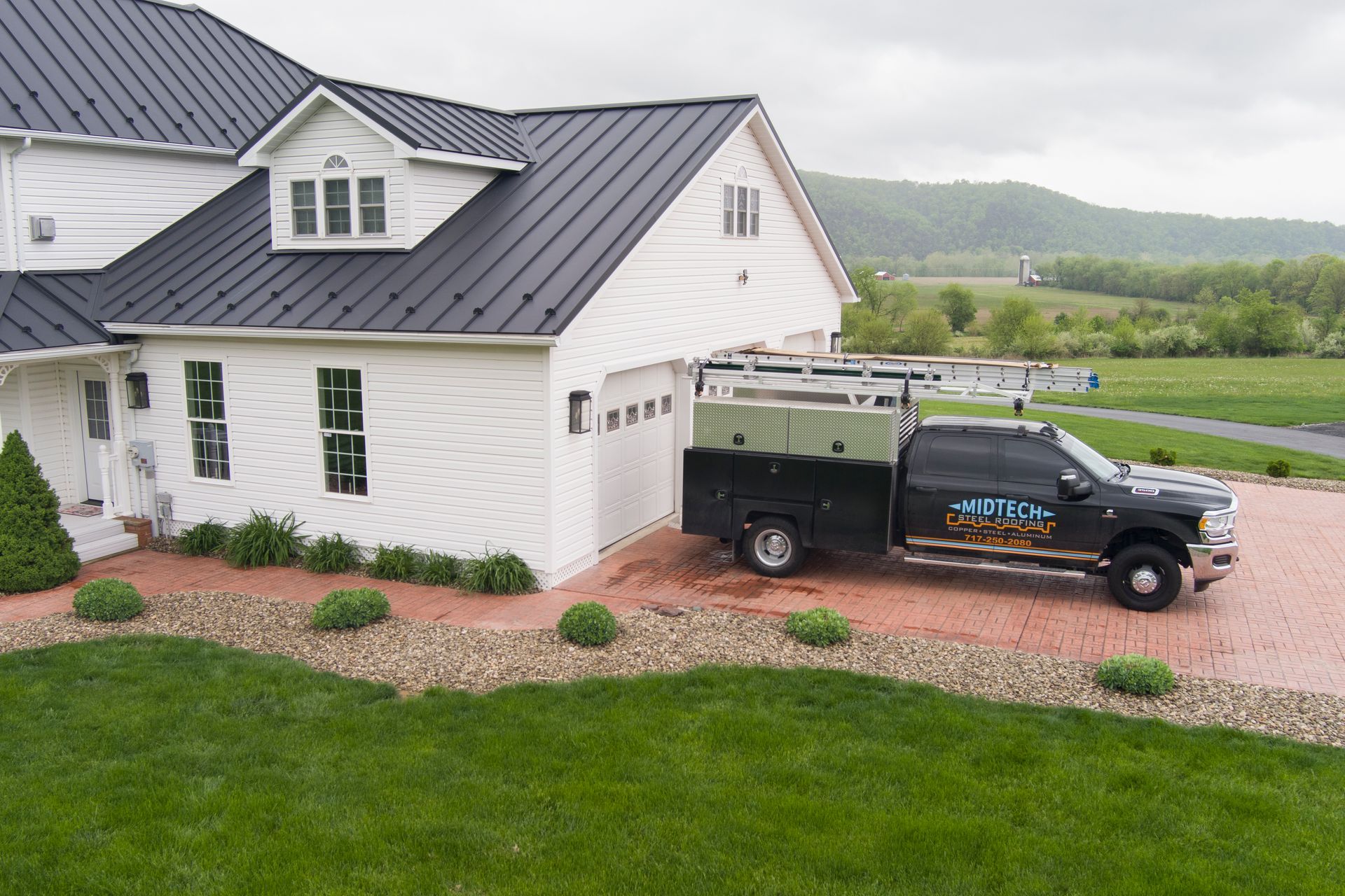 White house with black roof, service truck parked in front.
