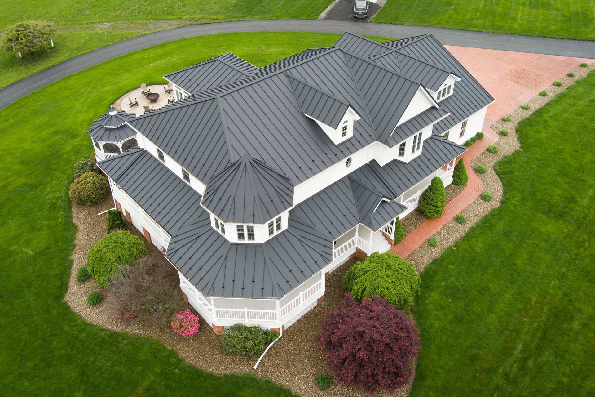 White house with dark roof, surrounded by green grass and landscaping.
