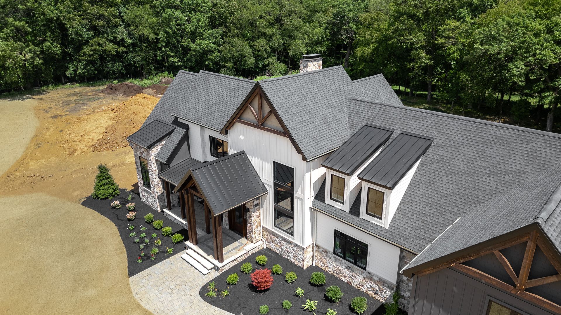 Modern farmhouse with gray roof and siding, stone accents, and landscaping.