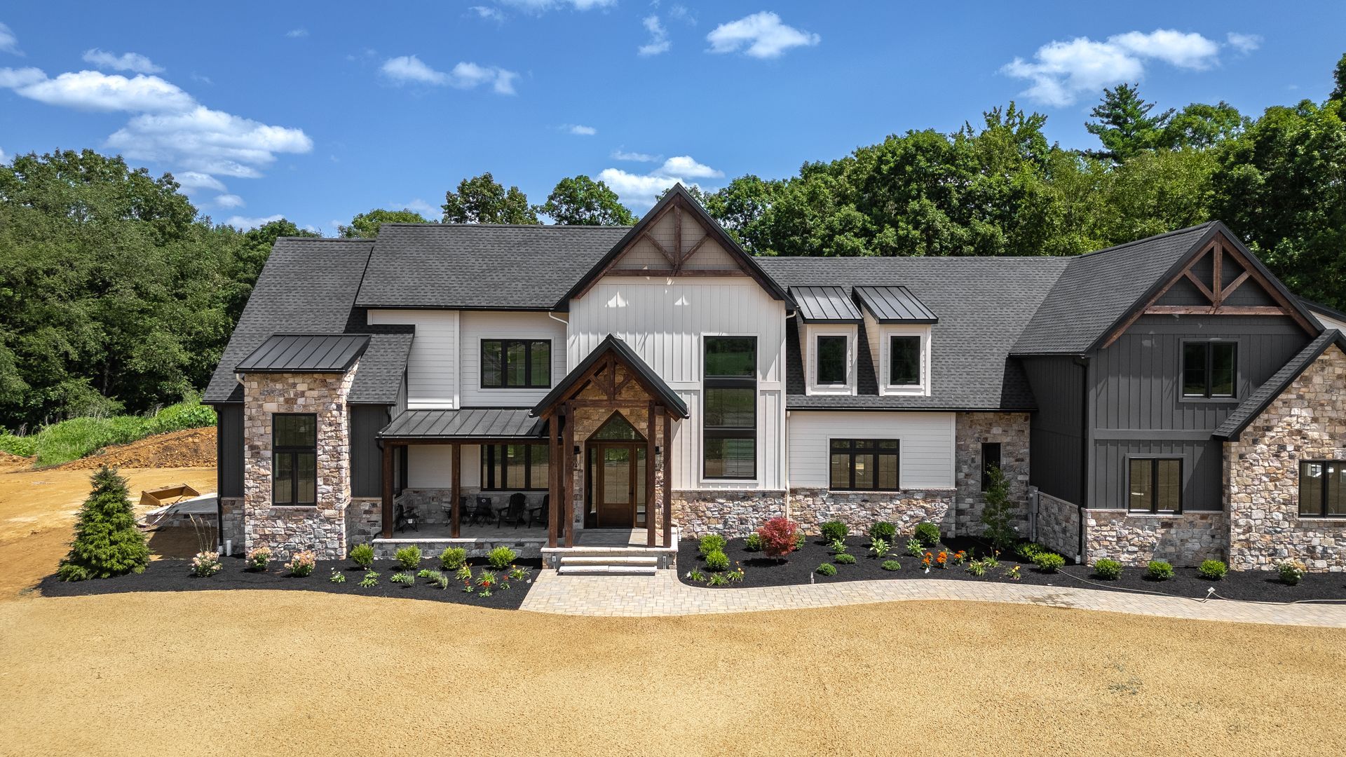 Modern house with stone and wood facade under blue sky.
