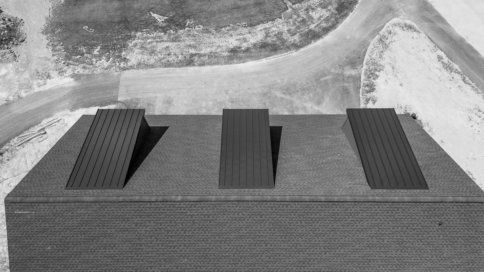 Aerial view of rooftop with three raised structures, driveway and grass by Midtech Standing Seam