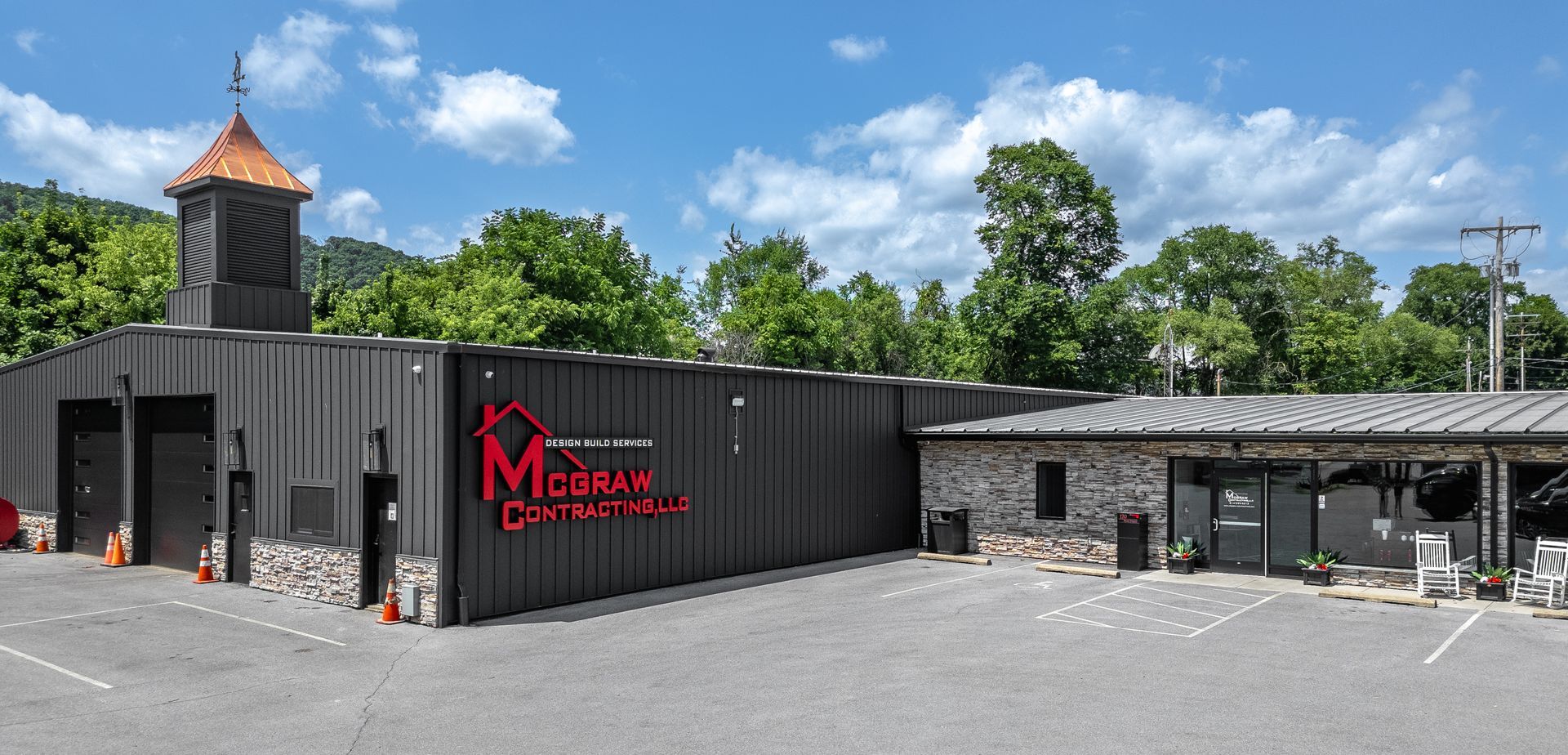 Exterior view of a distillery with a red sign, metal buildings, and a stone facade.