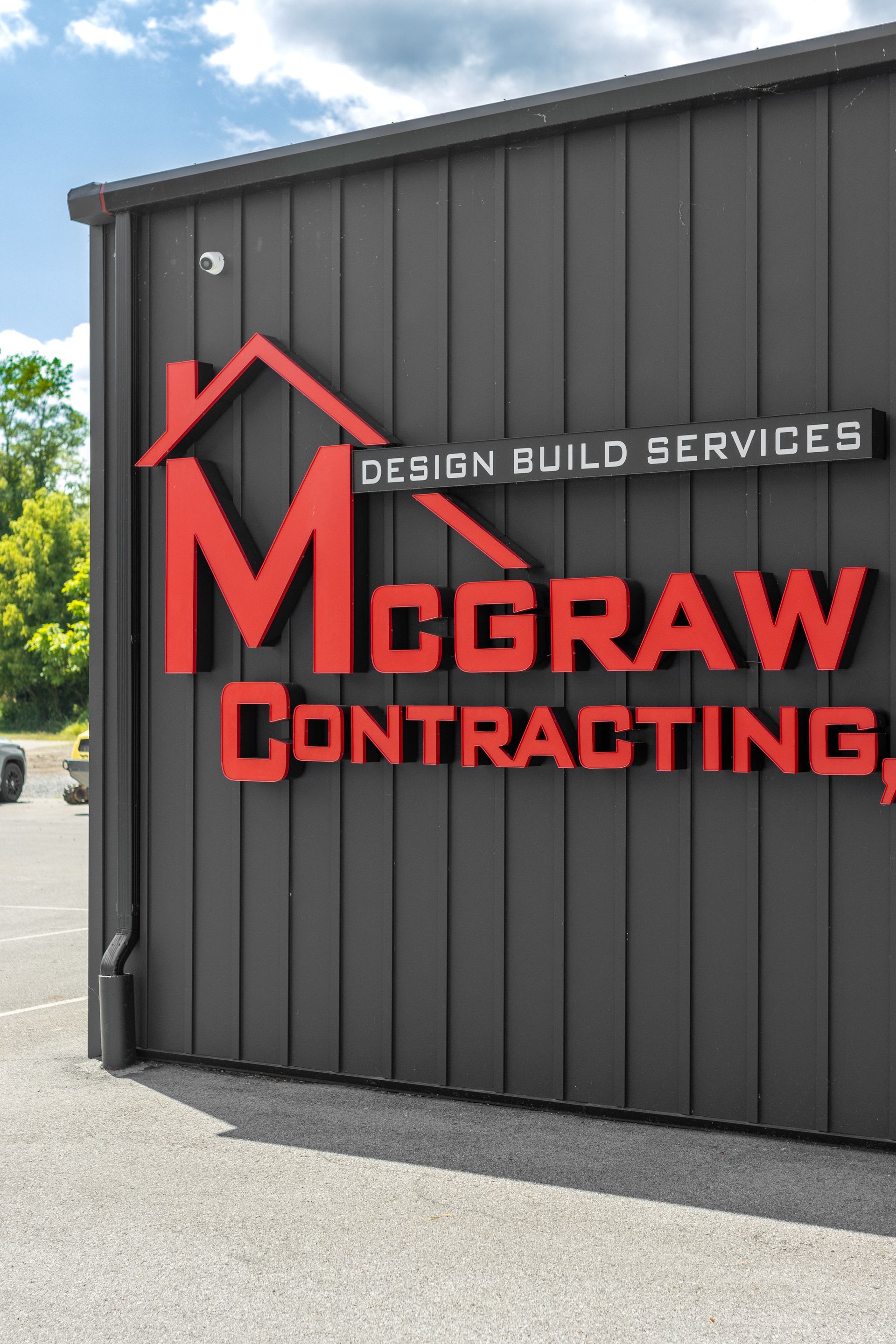 McGraw Contracting sign on a black building; red logo with roof outline, 