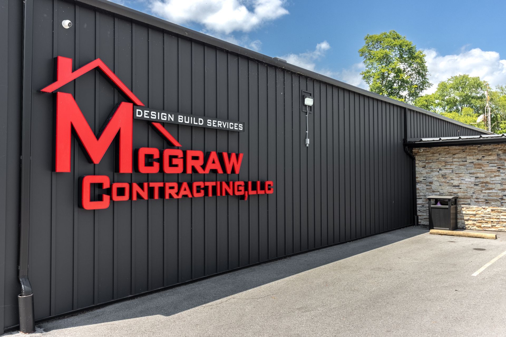 Red logo for McGraw Contracting LLC on a dark building, with 