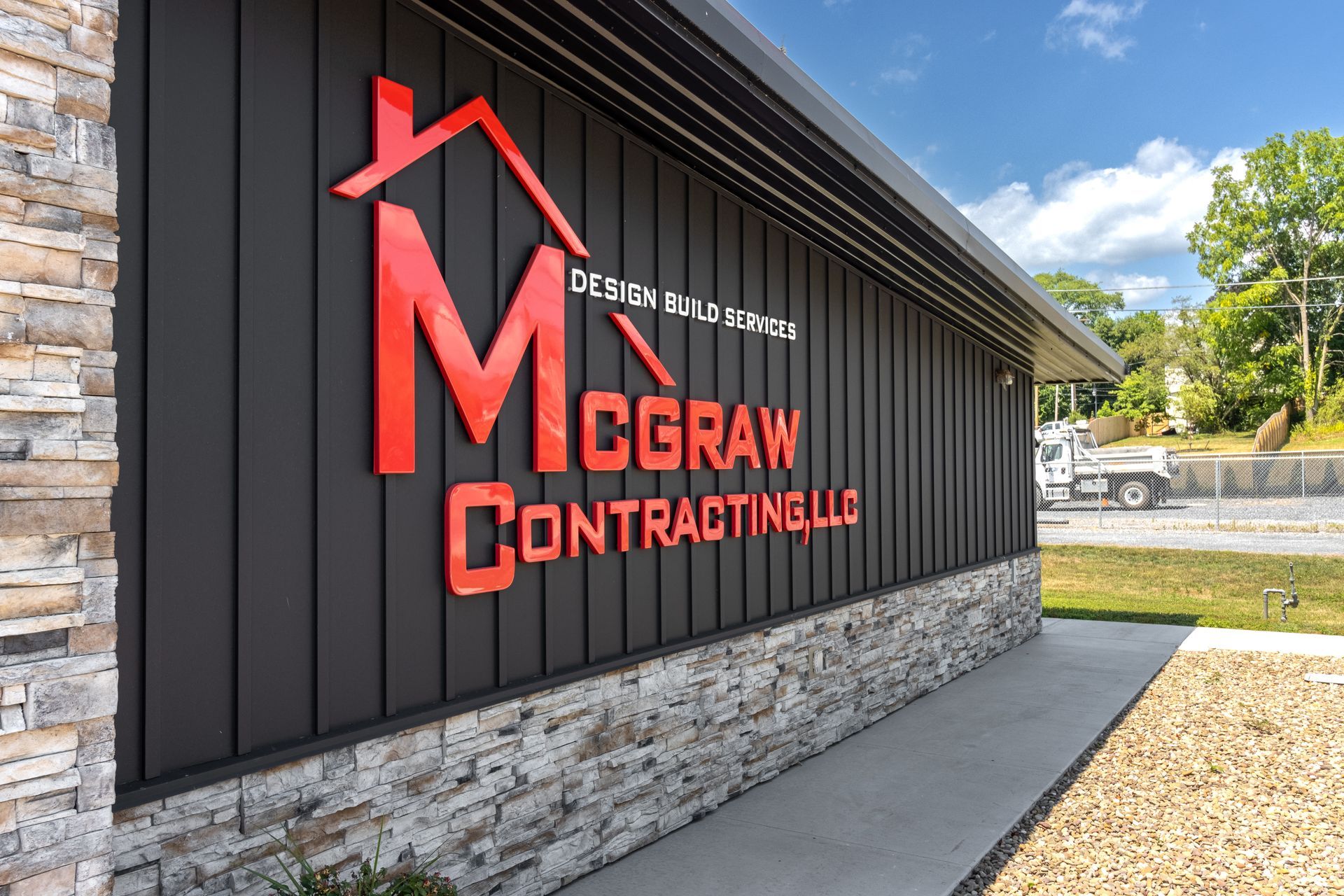 McGraw Contracting LLC building sign in red against a black facade with stone base.