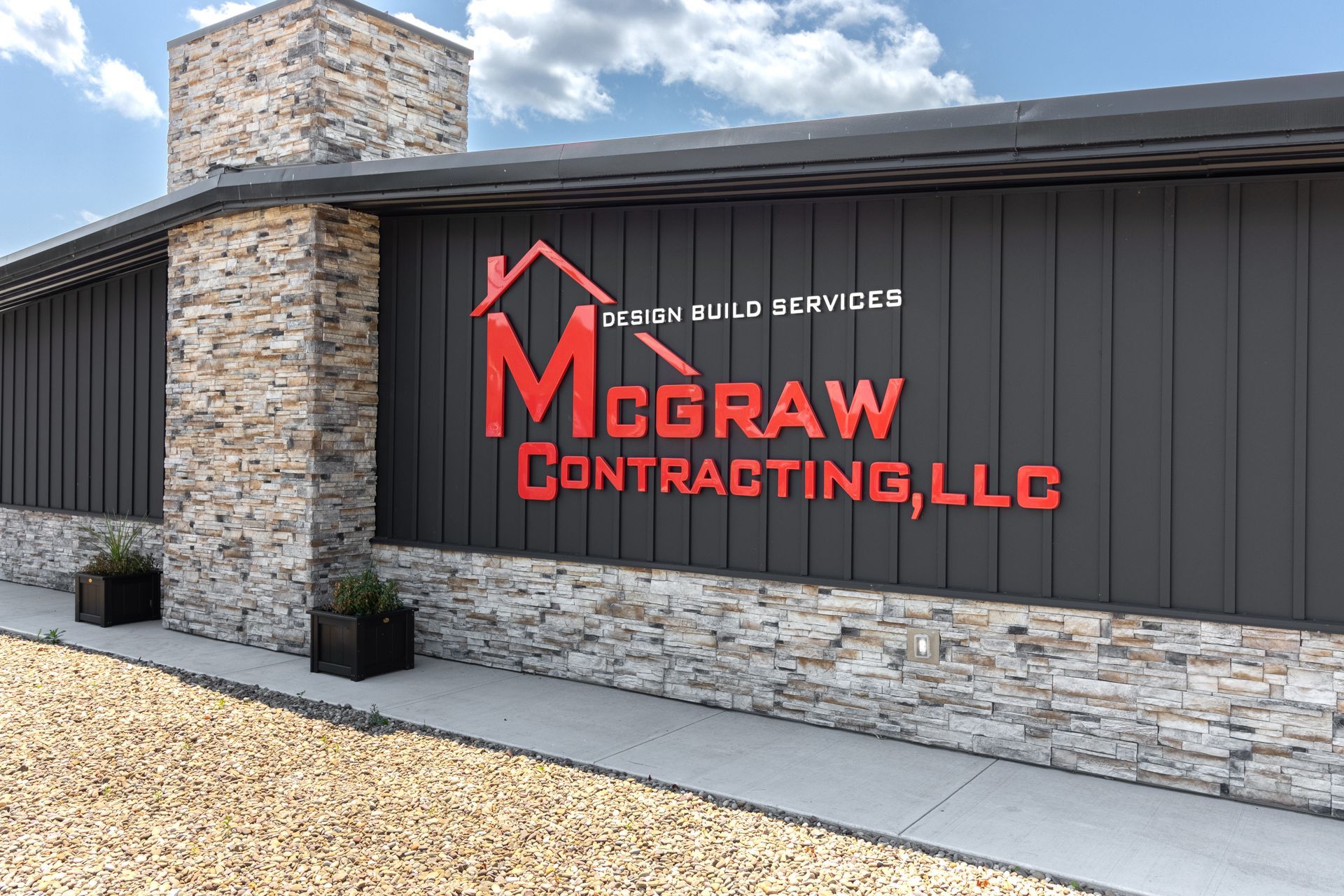 McGraw Contracting, LLC sign on a building with stone facade, red logo on black background.
