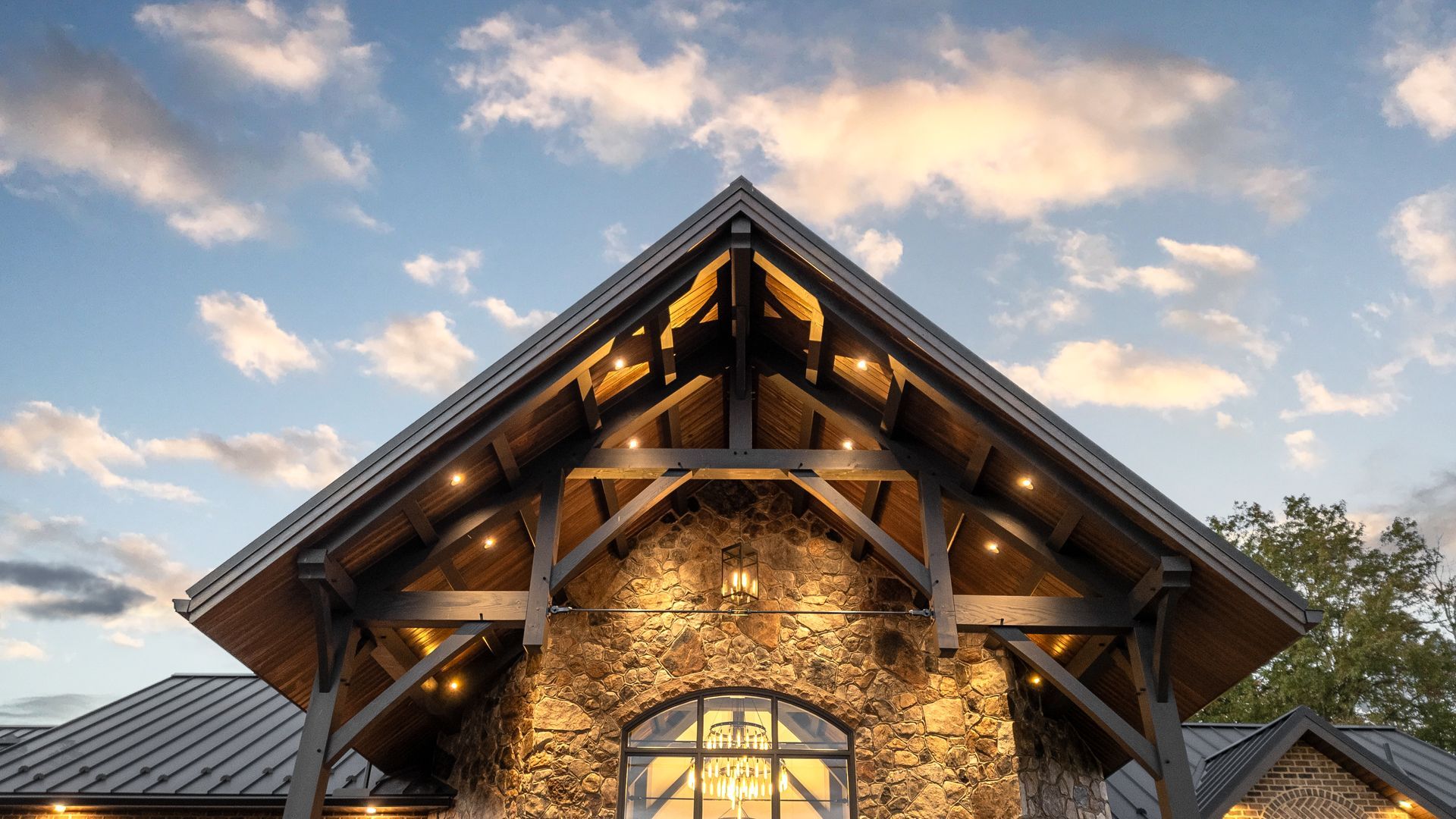 Stone building with exposed wooden beams, under a cloudy sky.