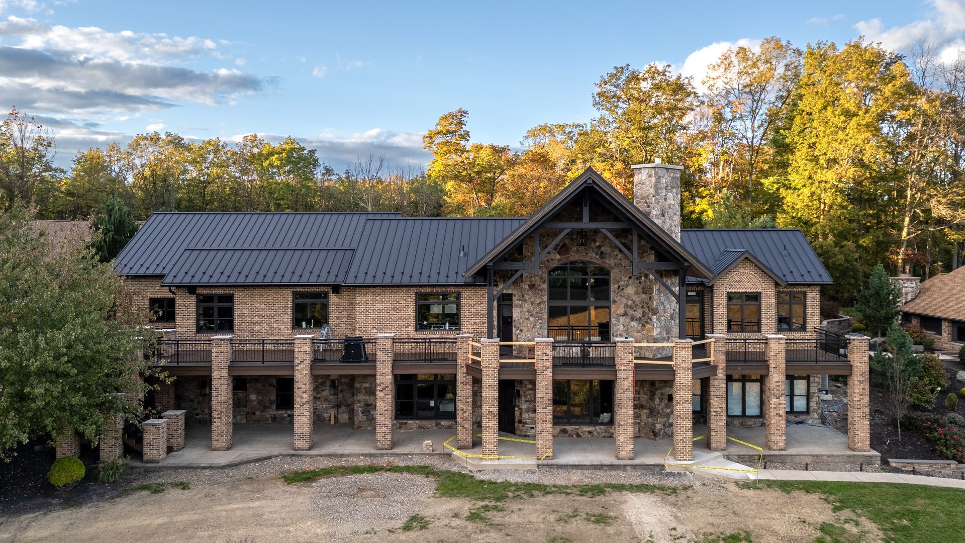 Large stone and wood house with black roof and multiple levels of balconies.