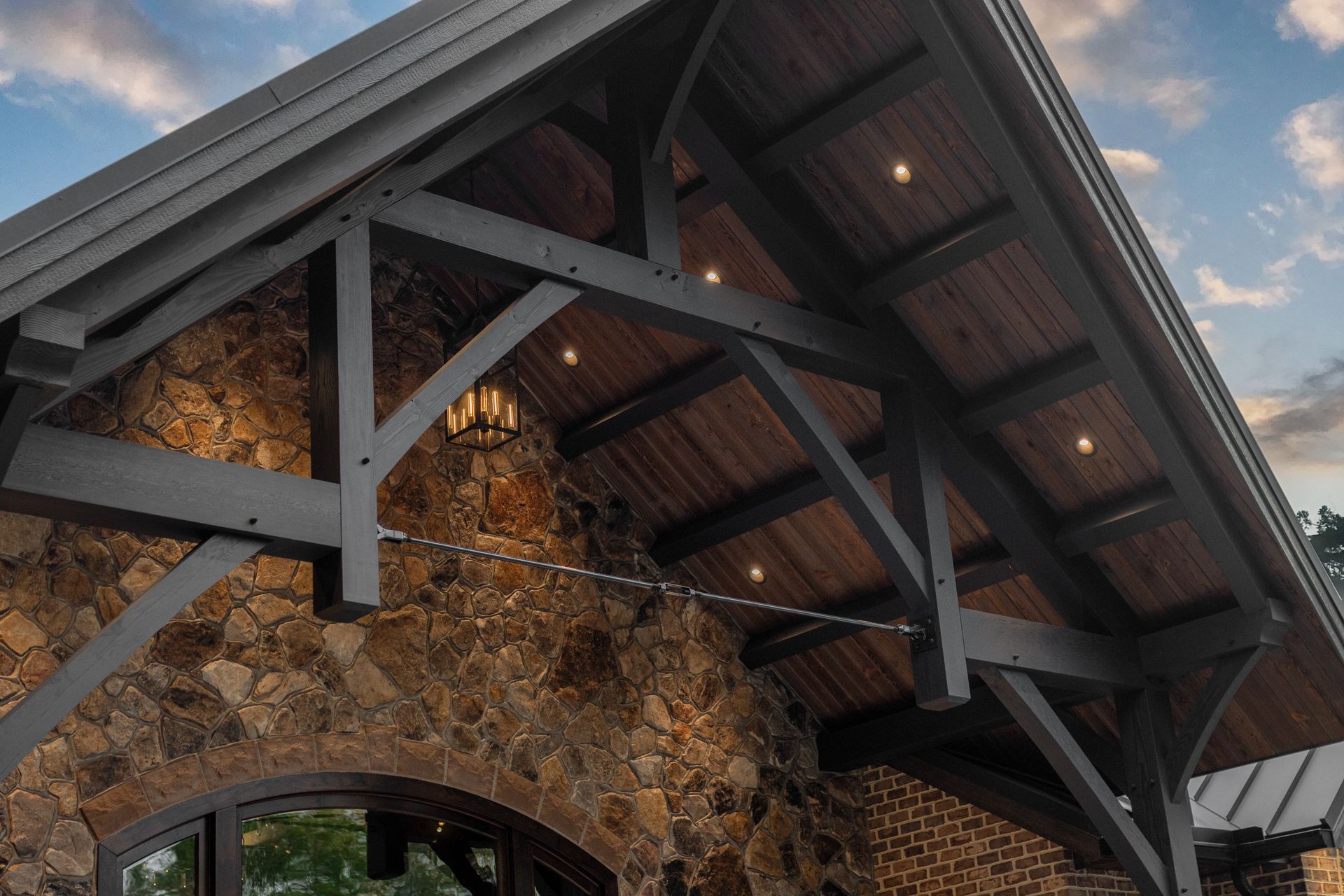 Stone building with a dark wood truss roof. Brown stone and brick walls.