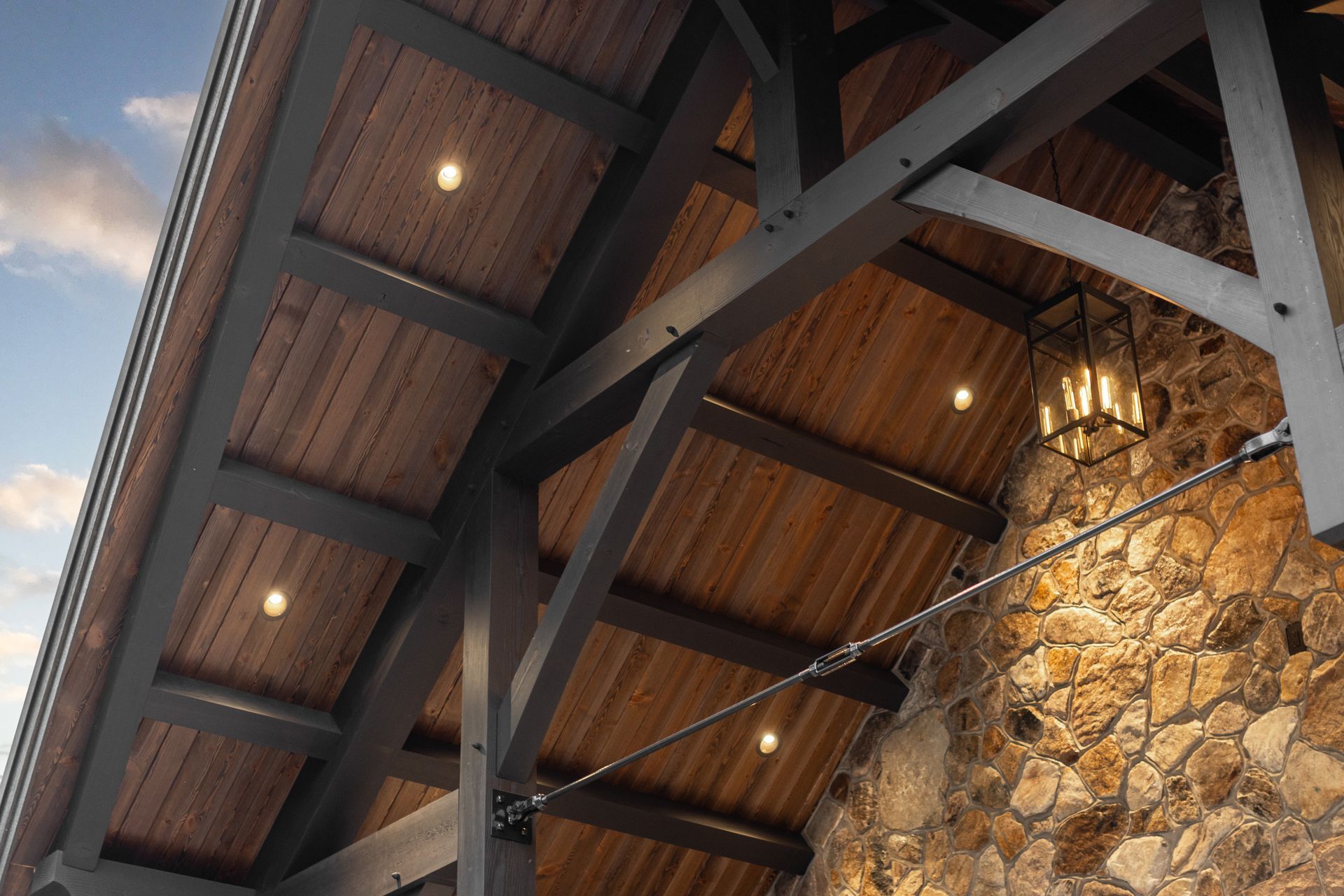 Wooden ceiling with dark beams, recessed lights, and stone wall.
