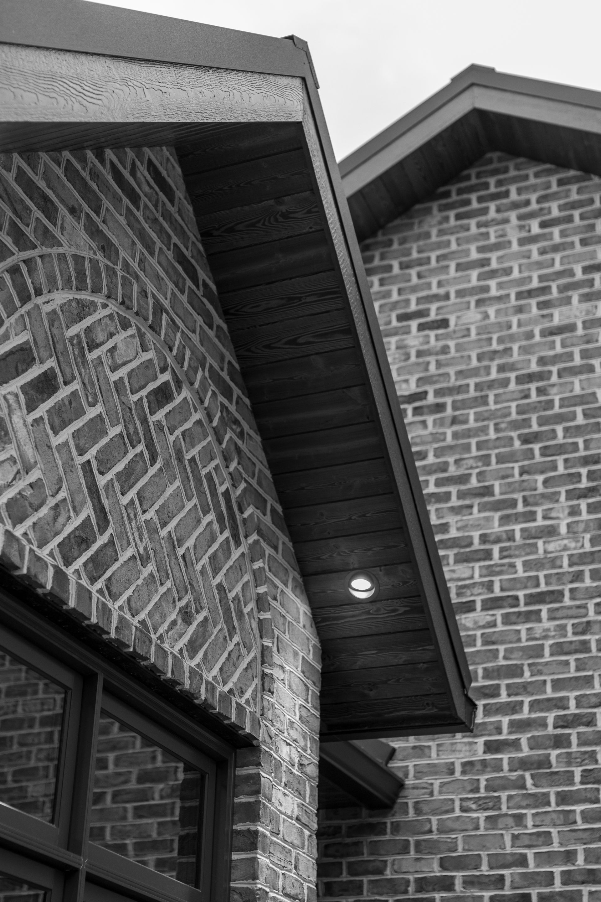 Brick building exterior with wooden eaves and a recessed light fixture.