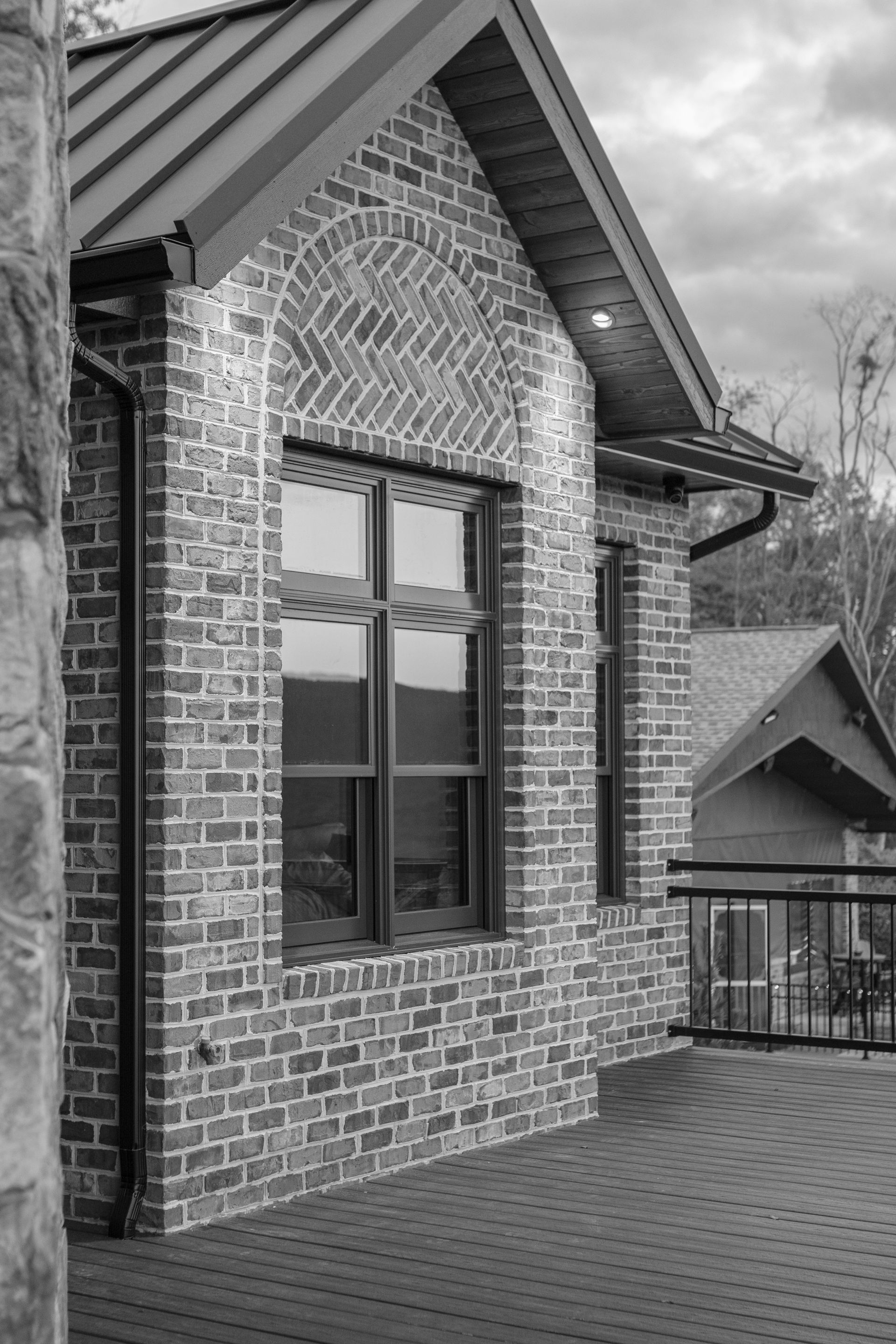 Brick building with arched window, black gutters, and a dark metal roof.