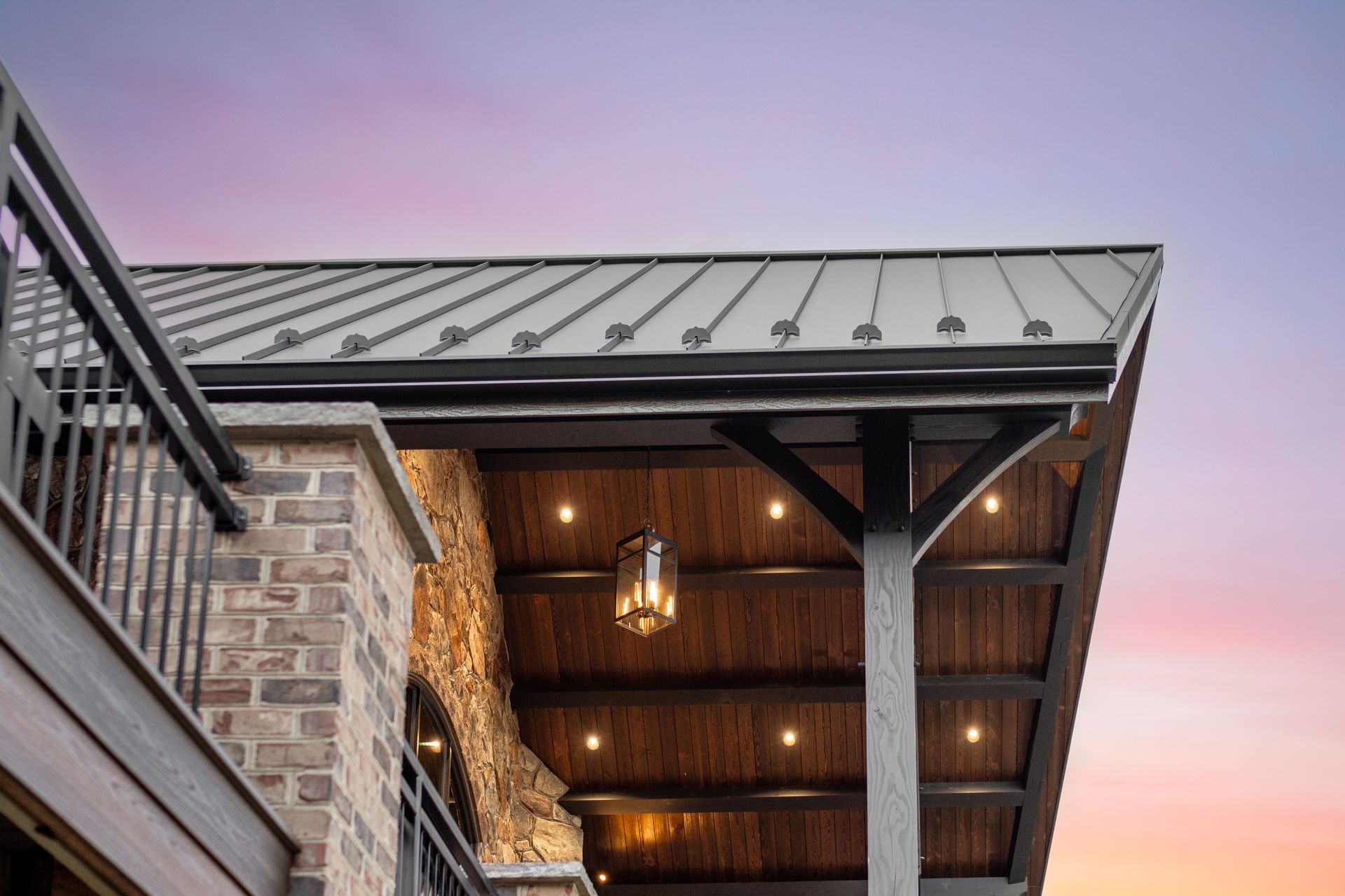 Patio roof with metal sheeting, wood beams, and hanging lantern against sunset.