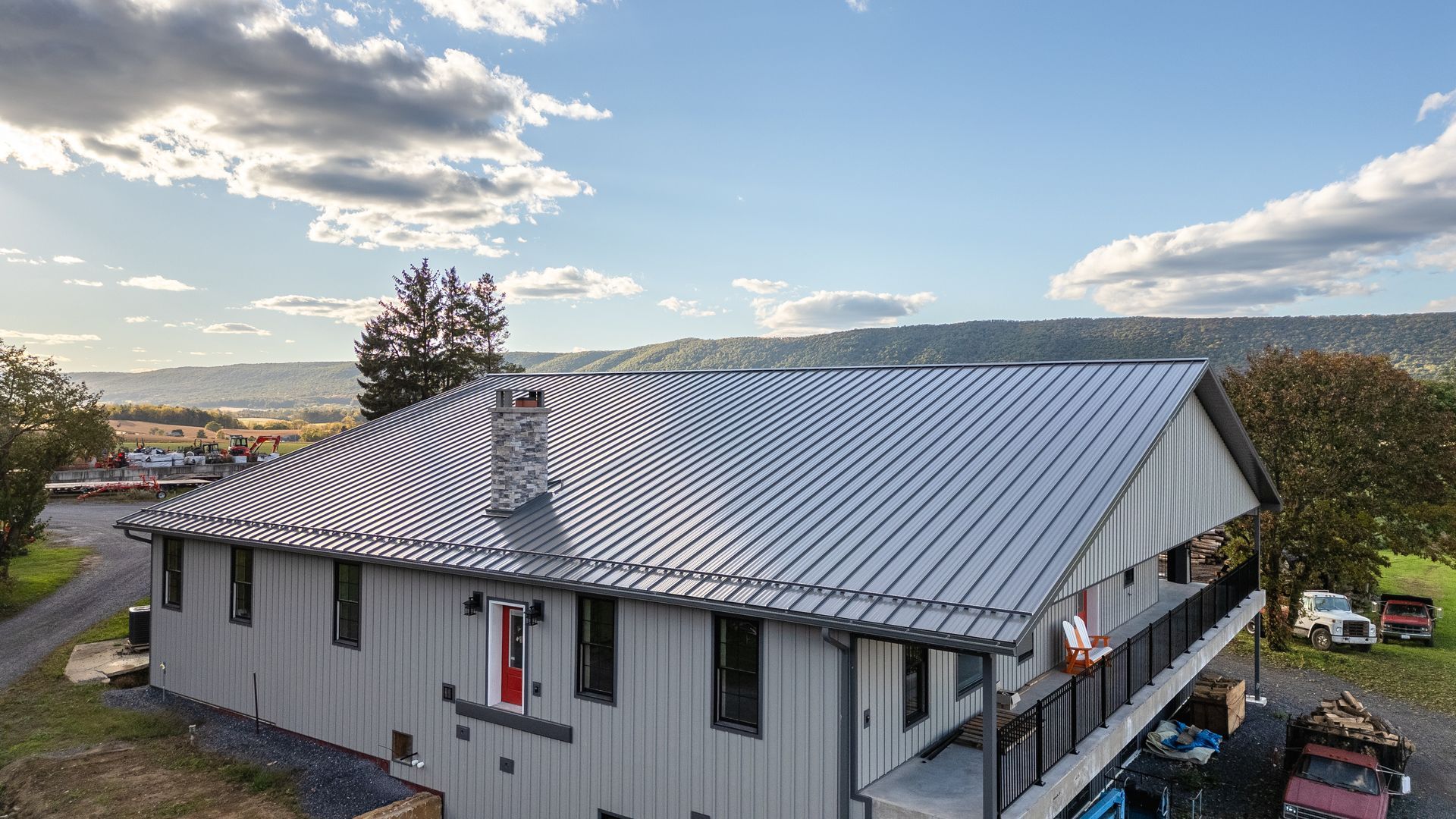 Grey building with a metal roof and a red door, with a landscape view.