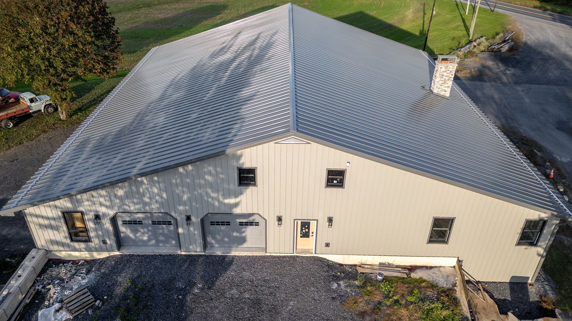 Gray metal-roofed building with multiple garage doors and a chimney.