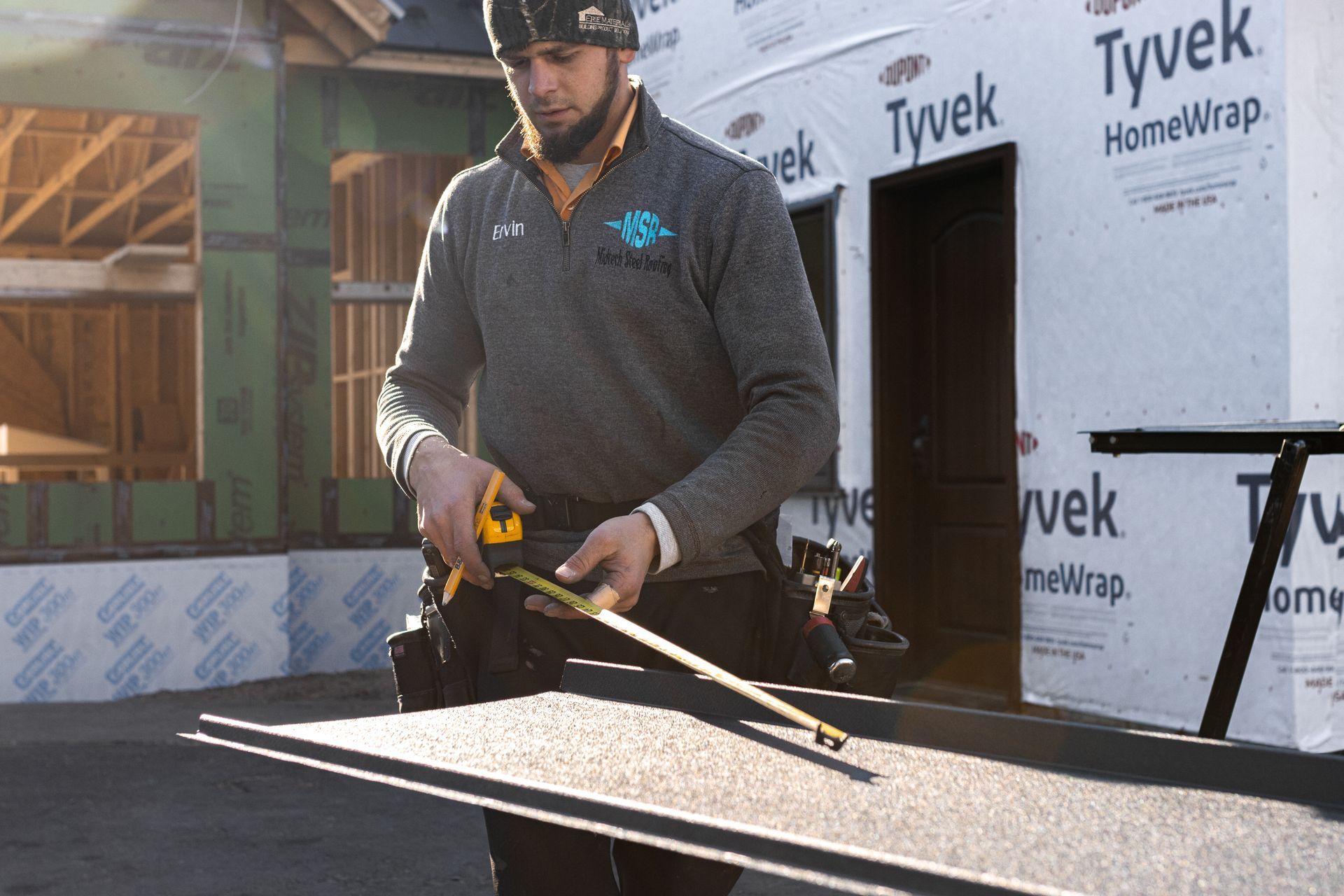Construction worker measuring material outside a building.