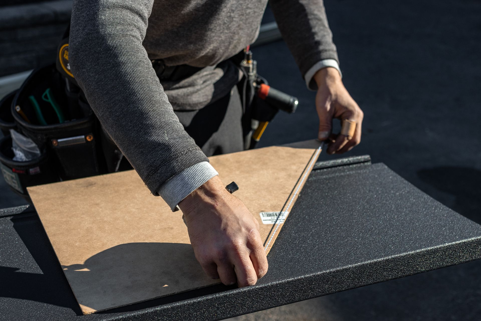Person working on a picture frame, outdoors. Hands manipulating the frame, possibly securing it.