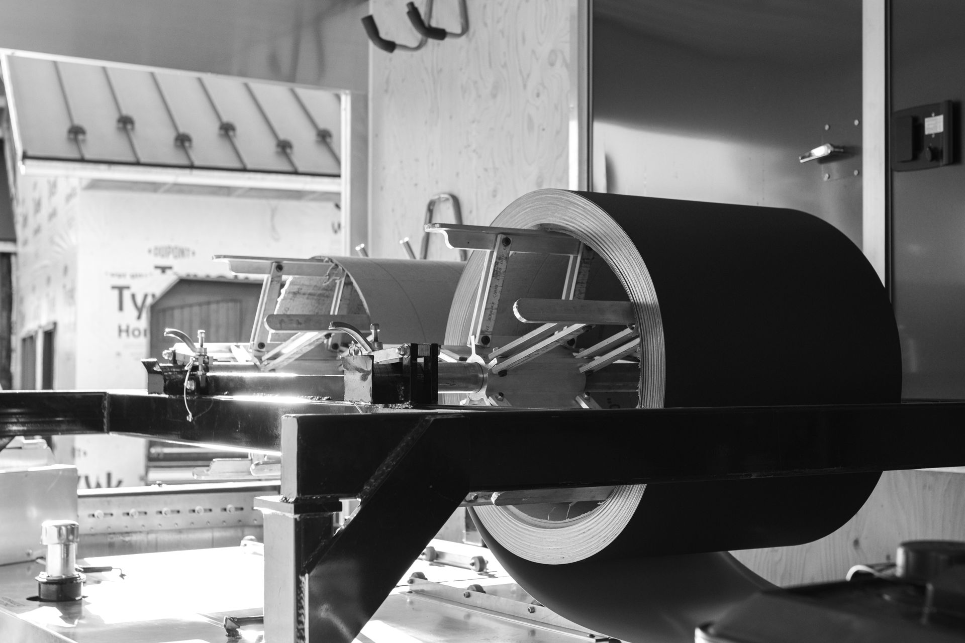 A large, cylindrical roll of material mounted on a machine with other equipment in a manufacturing setting.