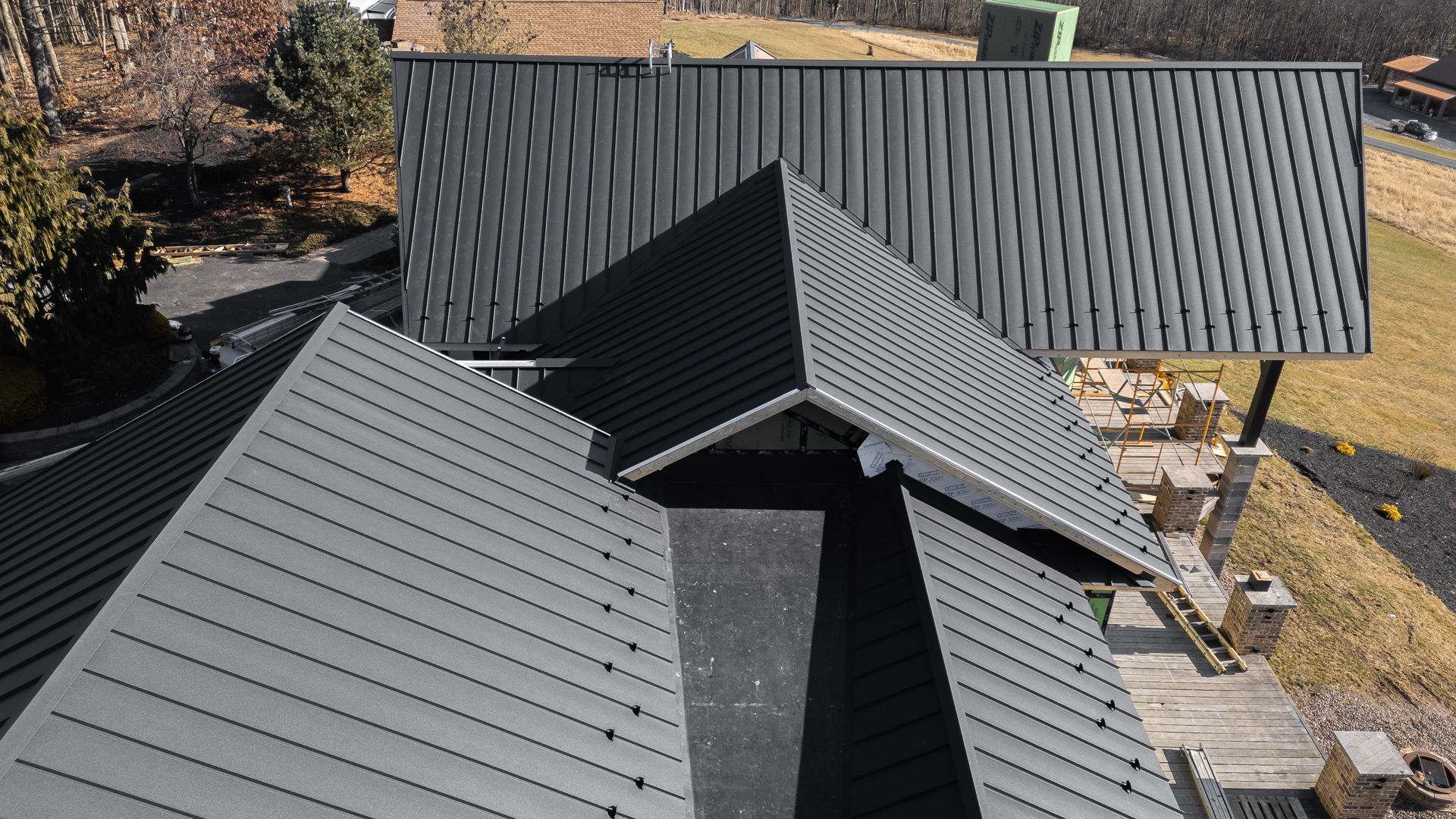 Overhead view of a black metal roof with multiple angles on a house; outdoor setting.